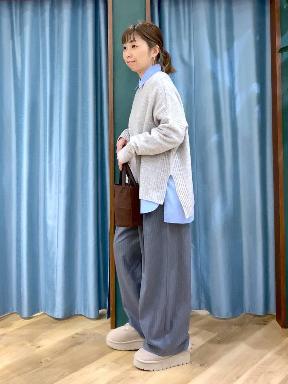 ブルー系のシャツ/ブラウス、ベージュ系のスリッポン、ベージュ系のニット/セーターを着用したレディースの冬コーディネートの3枚目の写真