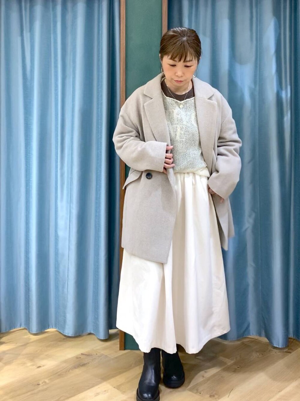 ブラック系のブーツ、ベージュ系のピーコート、ホワイト系のスカートを着用したレディースの冬コーディネートの6枚目の写真