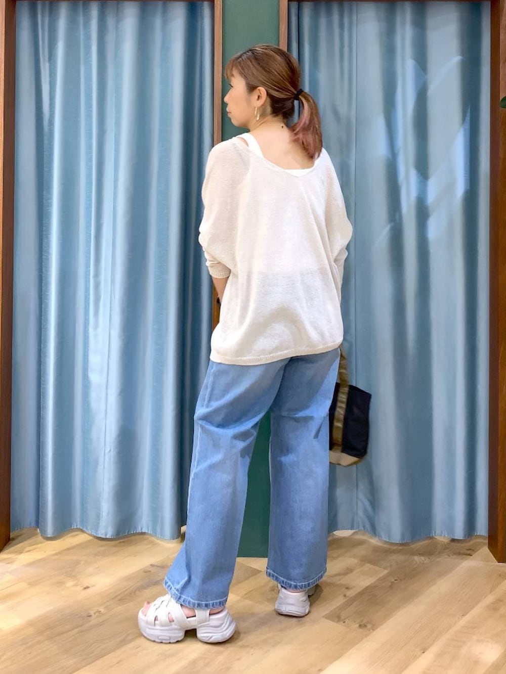 ブルー系のデニムパンツ、ホワイト系のタンクトップ、ホワイト系のニット/セーターを着用したレディースの春コーディネートの5枚目の写真