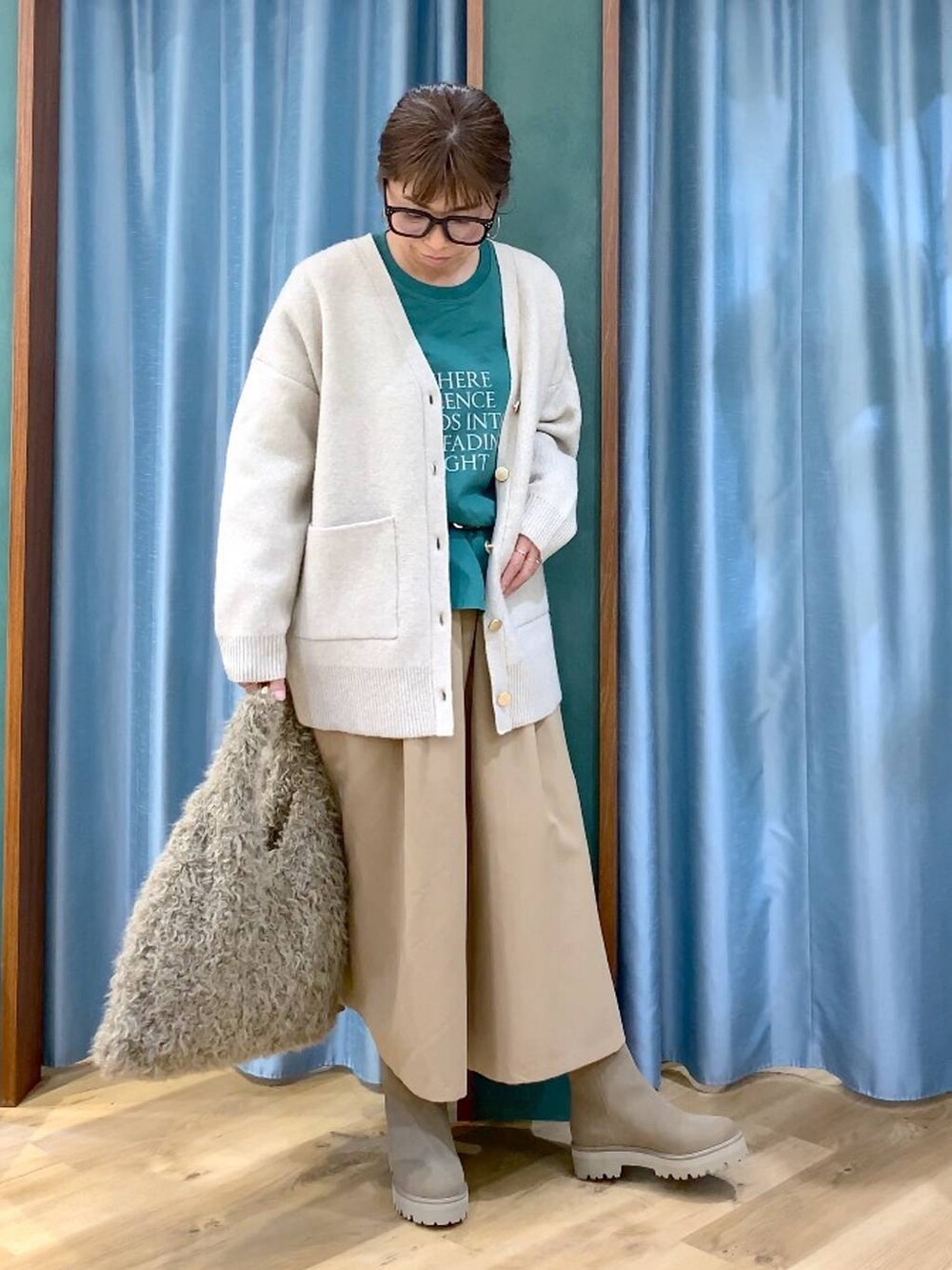 ベージュ系のハンドバッグ、ベージュ系のブーツ、グリーン系のTシャツ/カットソーを着用したレディースの冬コーディネートの4枚目の写真