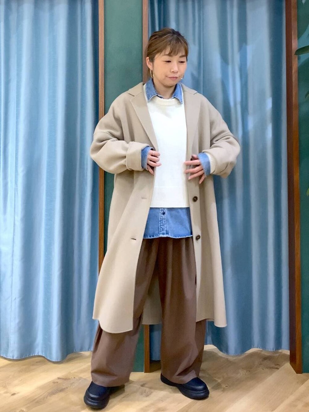 ブルー系のシャツ/ブラウス、ベージュ系のチェスターコート、ホワイト系のニット/セーターを着用したレディースの冬コーディネートの5枚目の写真