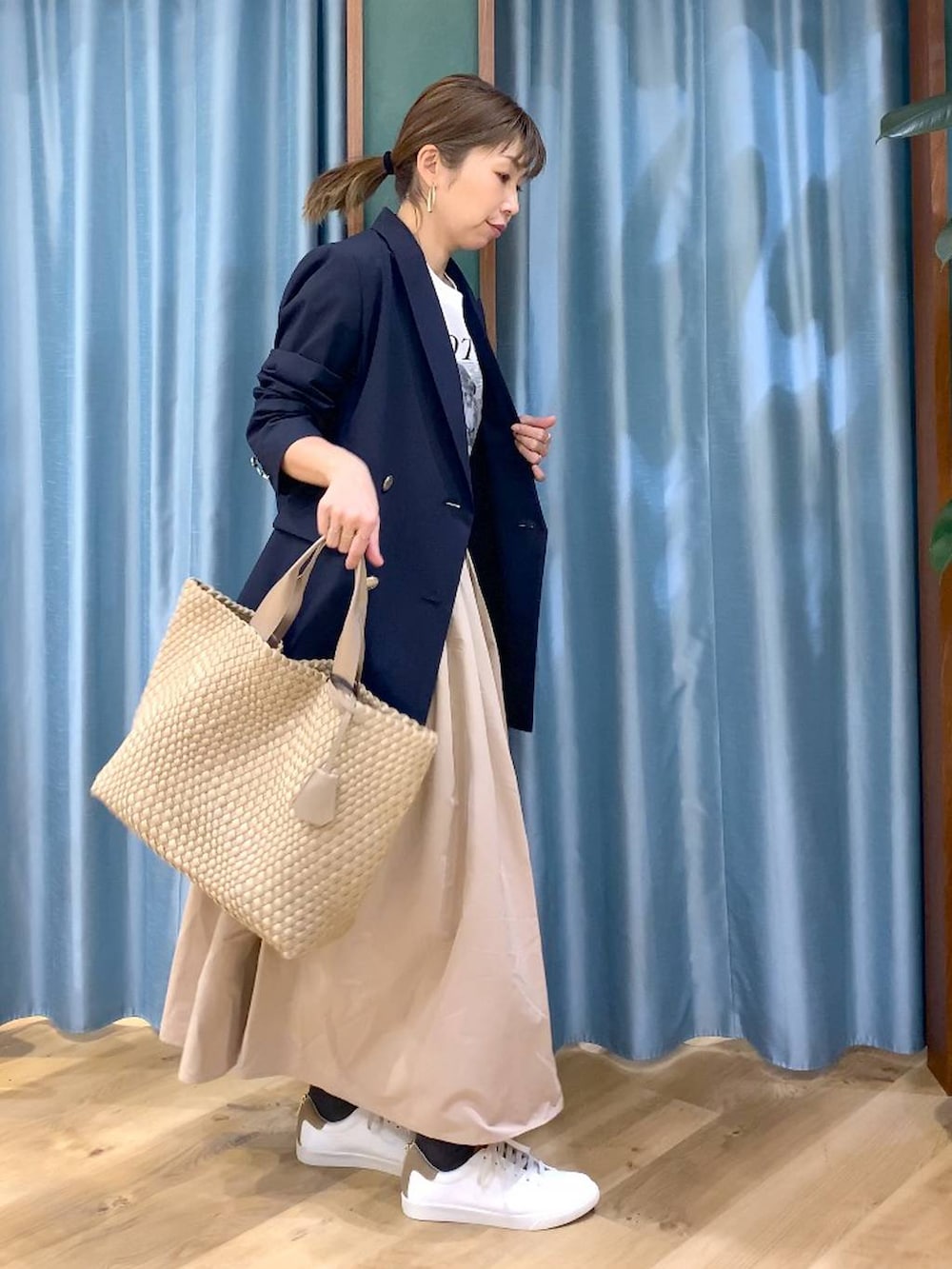 ベージュ系のスカート、ブルー系のテーラードジャケット、ベージュ系のトートバッグを着用したレディースの冬コーディネートの2枚目の写真