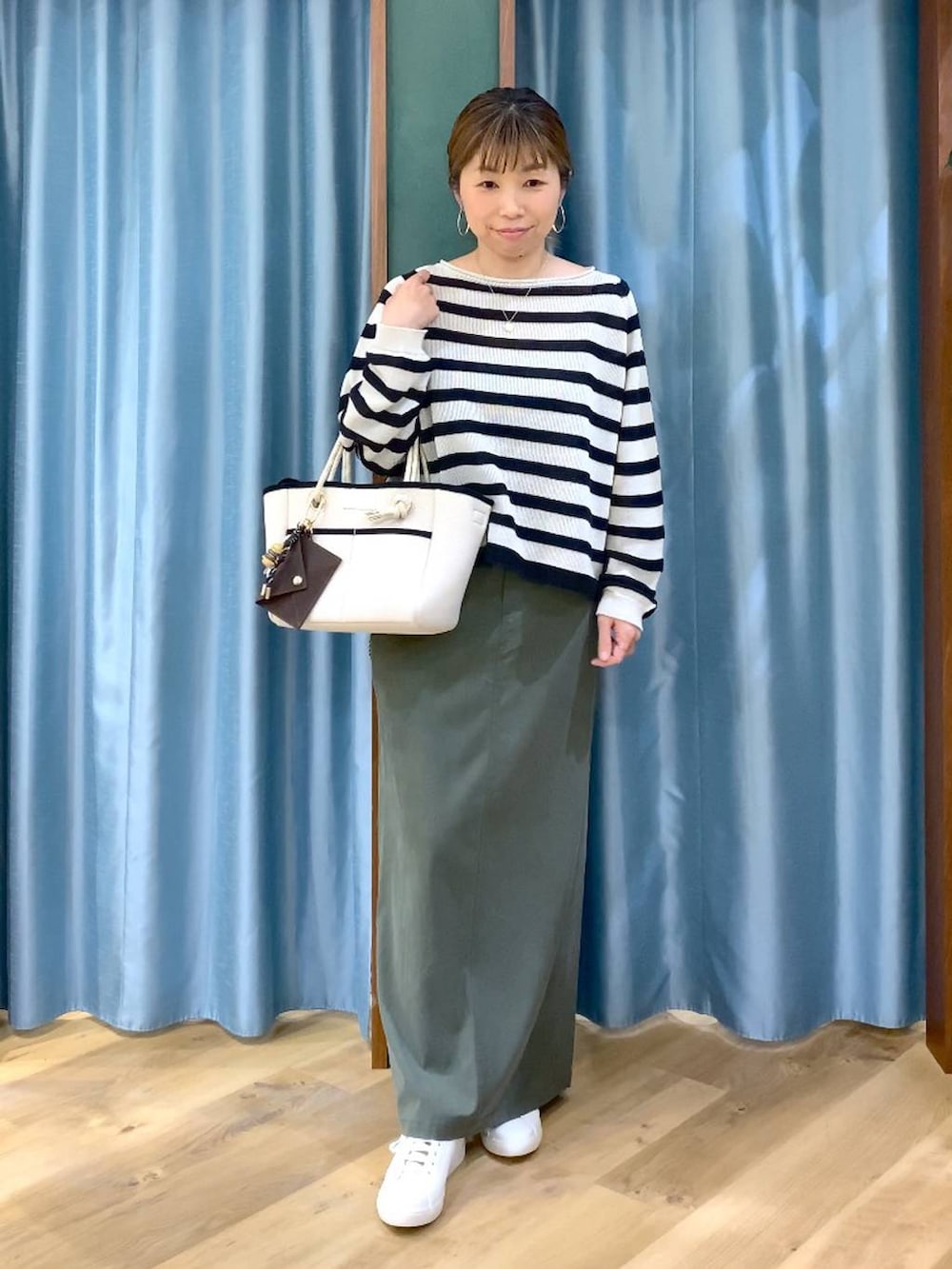 ベージュ系のニット/セーター、グリーン系のスカート、ホワイト系のトートバッグを着用したレディースの春コーディネートの4枚目の写真