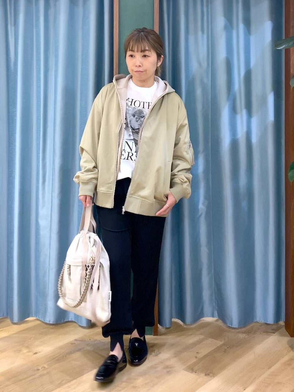 ベージュ系のパーカー、グリーン系のMA-1、ホワイト系のTシャツ/カットソーを着用したレディースの冬コーディネートの2枚目の写真