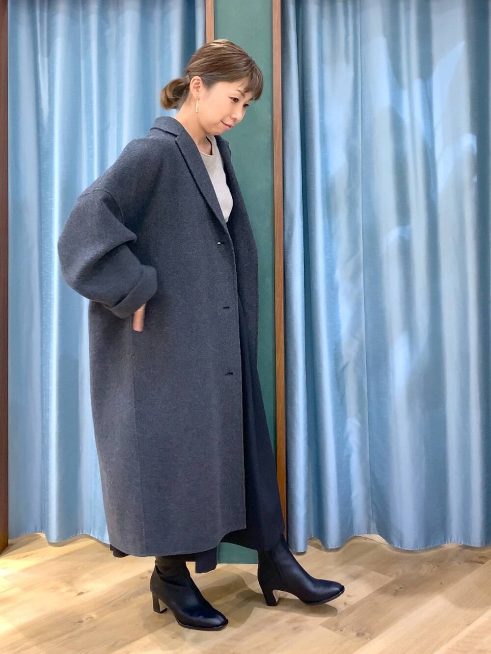 グレー系のチェスターコート、ブラック系のブーツ、ベージュ系のニット/セーターを着用したレディースの冬コーディネートの4枚目の写真