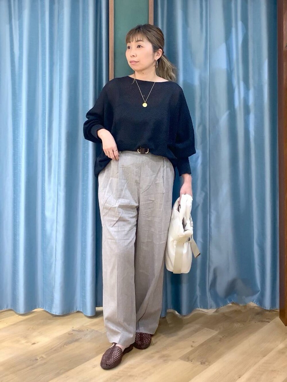 ブラック系のニット/セーター、ベージュ系のその他パンツ、ホワイト系のトートバッグを着用したレディースの春コーディネートの2枚目の写真