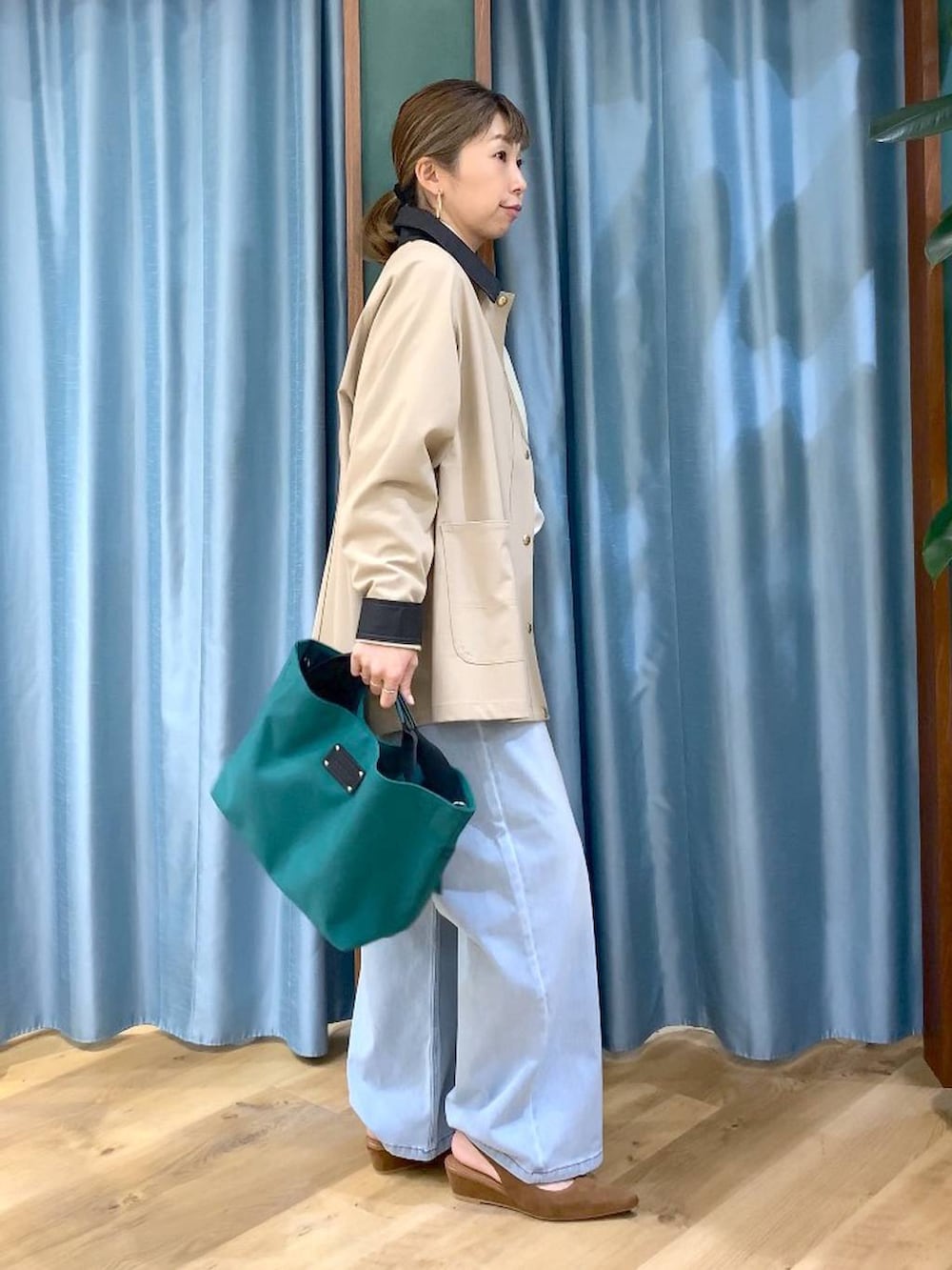 グリーン系のトートバッグ、ブルー系のデニムパンツ、ベージュ系のカバーオールを着用したレディースの冬コーディネートの6枚目の写真