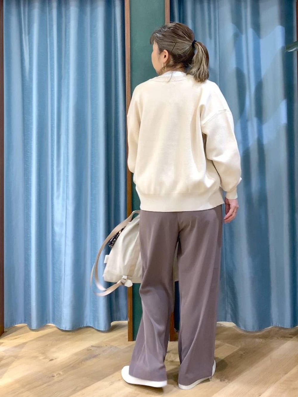 グリーン系のスラックス、ホワイト系のカーディガン/ボレロ、ベージュ系のバックパック/リュックを着用したレディースの冬コーディネートの3枚目の写真