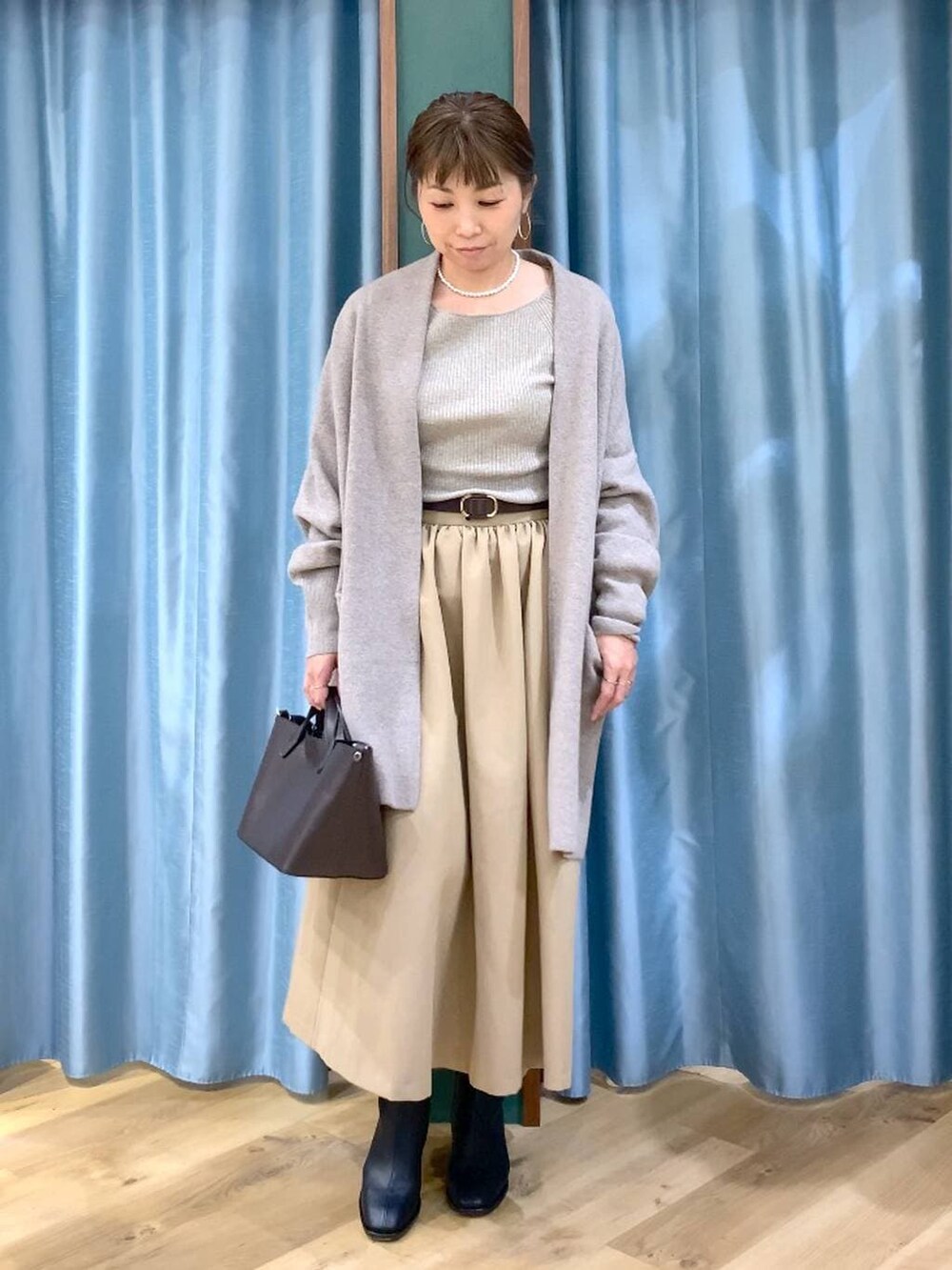 ブラック系のブーツ、ベージュ系のニット/セーター、ブラウン系のショルダーバッグを着用したレディースの秋コーディネートの3枚目の写真