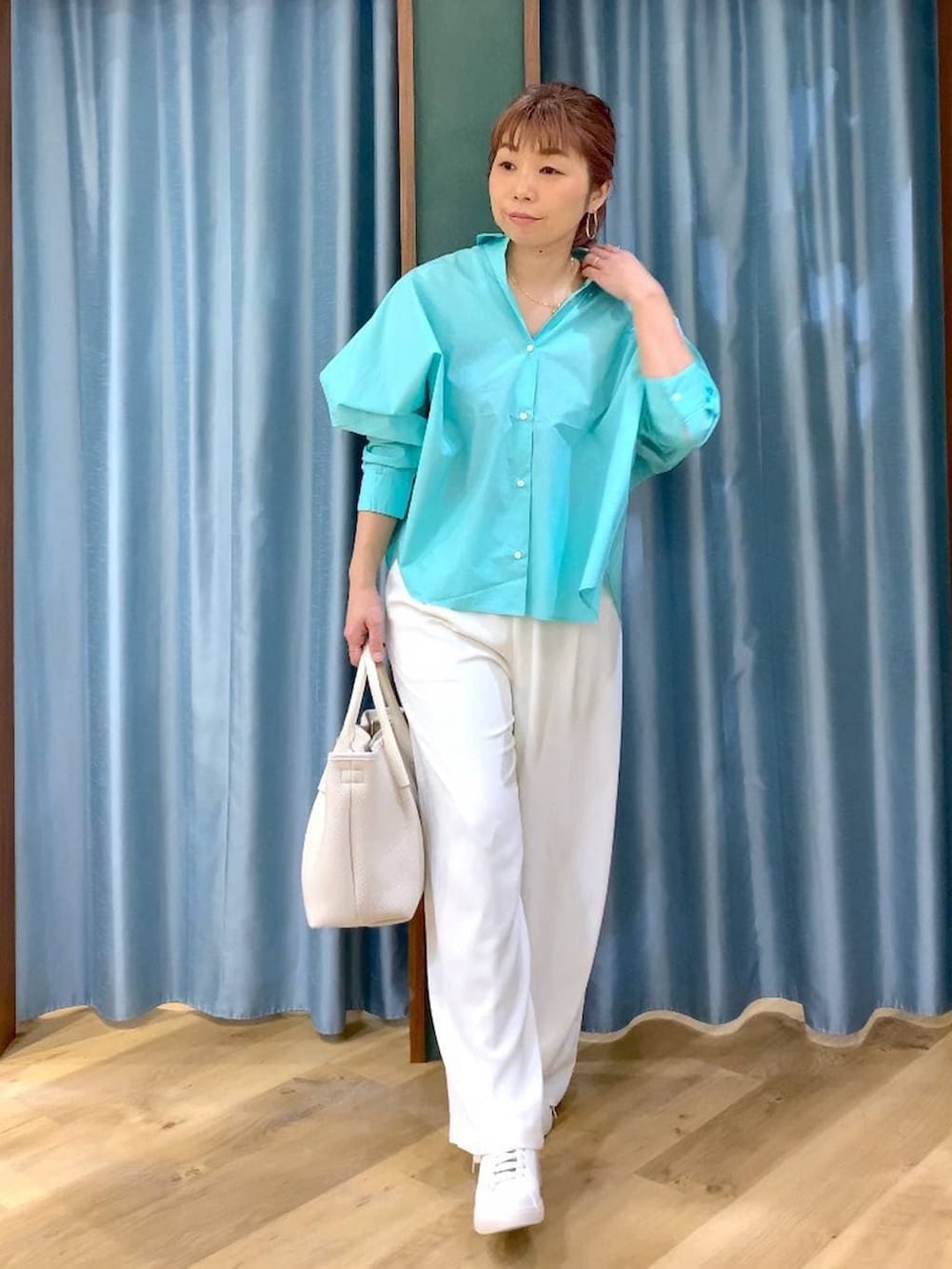 ホワイト系のスラックス、ブルー系のシャツ/ブラウス、ブラウン系のスニーカーを着用したレディースの春コーディネートの2枚目の写真