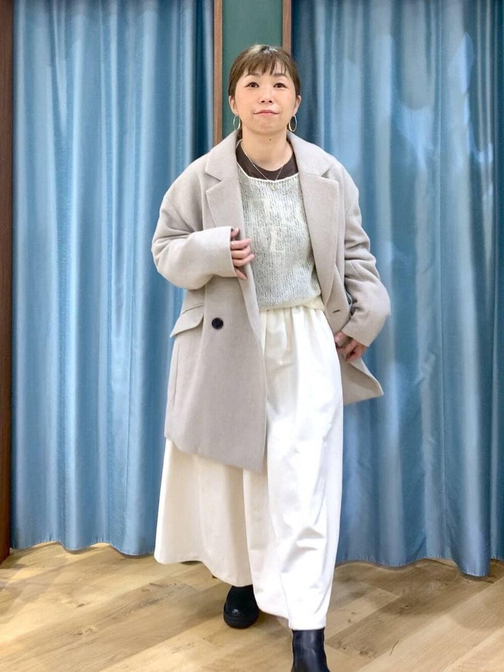 ブラック系のブーツ、ベージュ系のピーコート、ホワイト系のスカートを着用したレディースの冬コーディネートの8枚目の写真