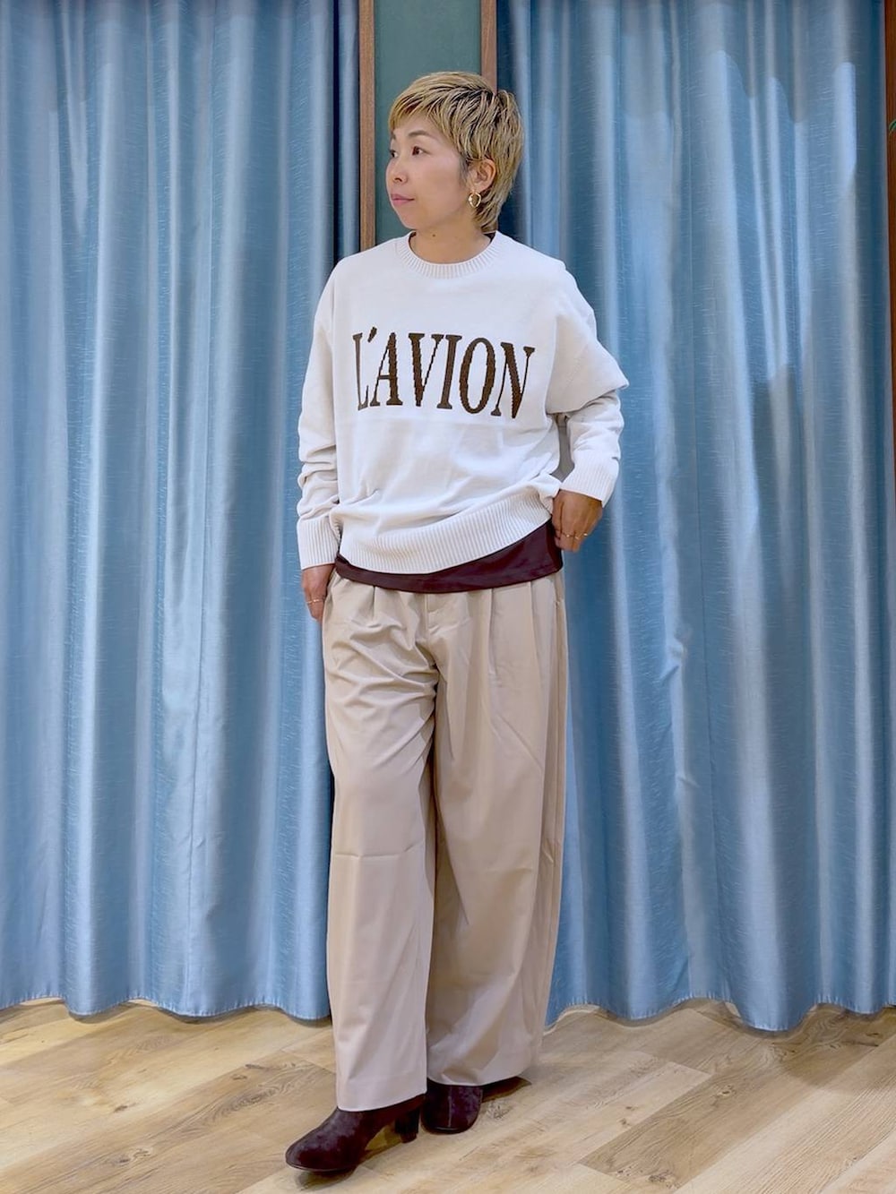 ブラウン系のTシャツ/カットソー、ブラウン系のブーツ、ホワイト系のニット/セーターを着用したレディースの秋コーディネートの2枚目の写真