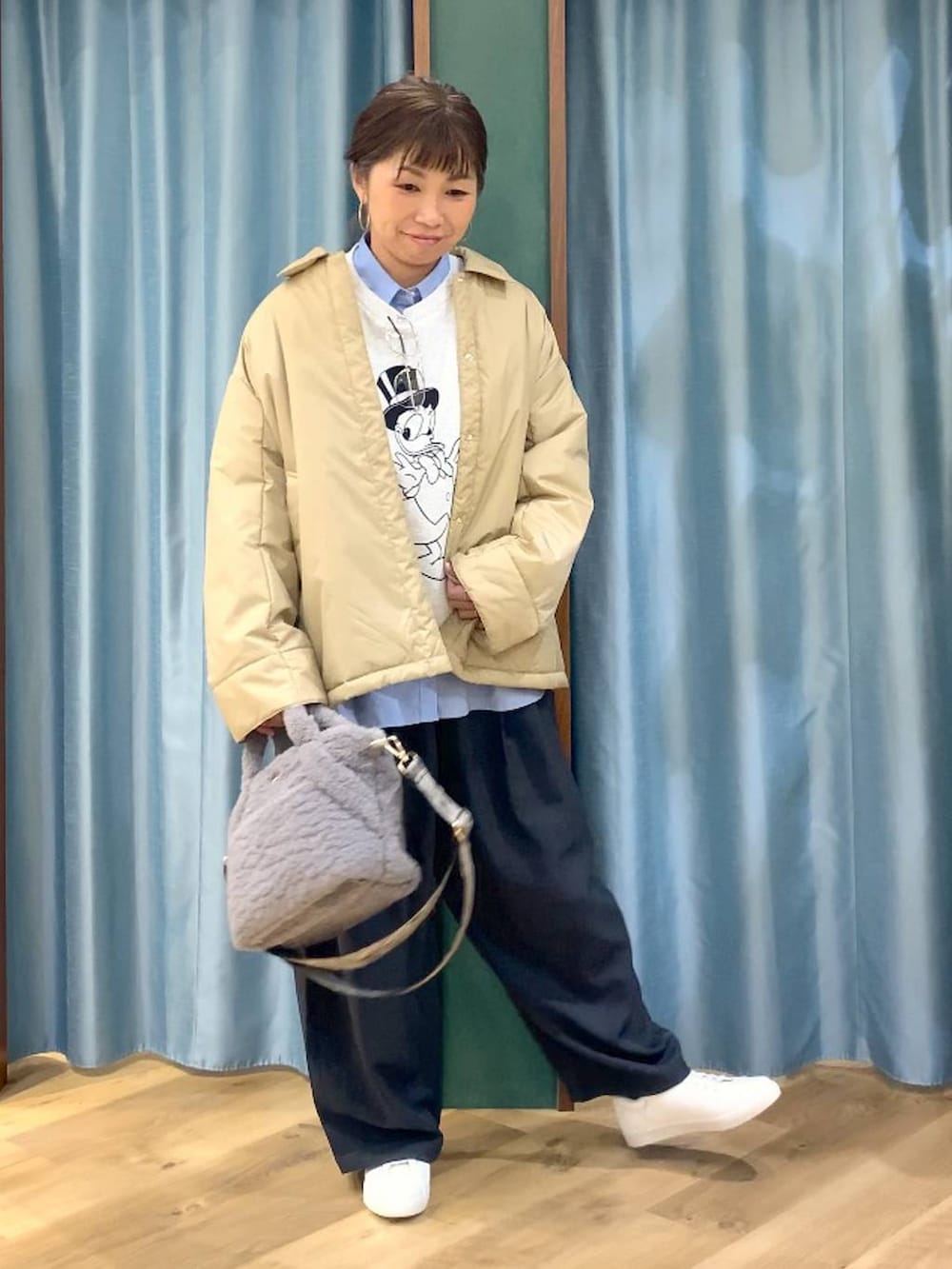 ベージュ系のブルゾン、ブルー系のシャツ/ブラウス、グレー系のスラックスを着用したレディースの秋コーディネートの2枚目の写真