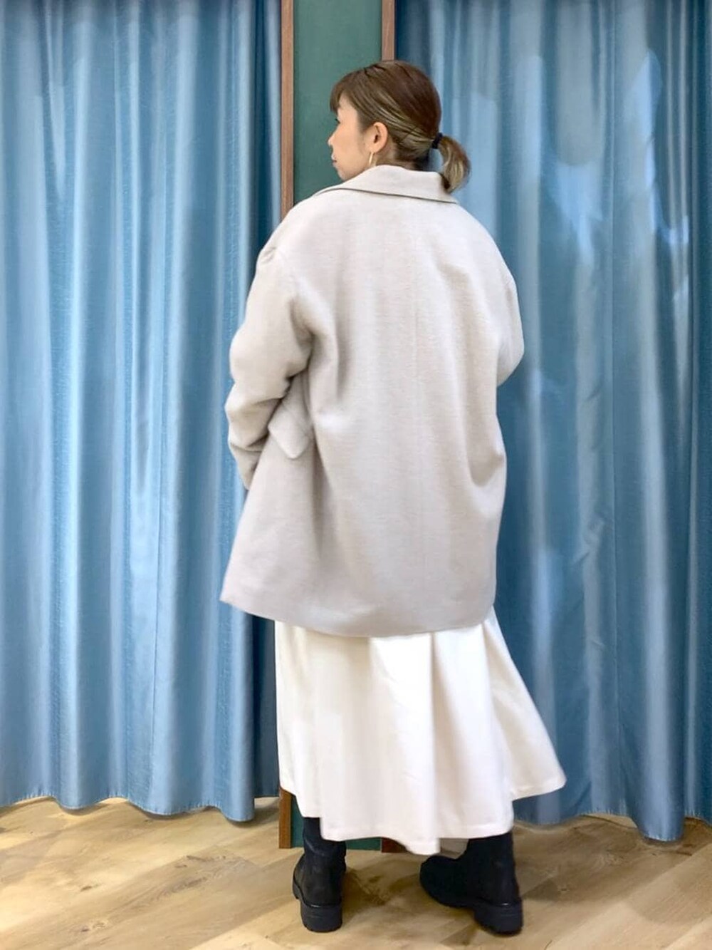 ブラック系のブーツ、ベージュ系のピーコート、ホワイト系のスカートを着用したレディースの冬コーディネートの3枚目の写真