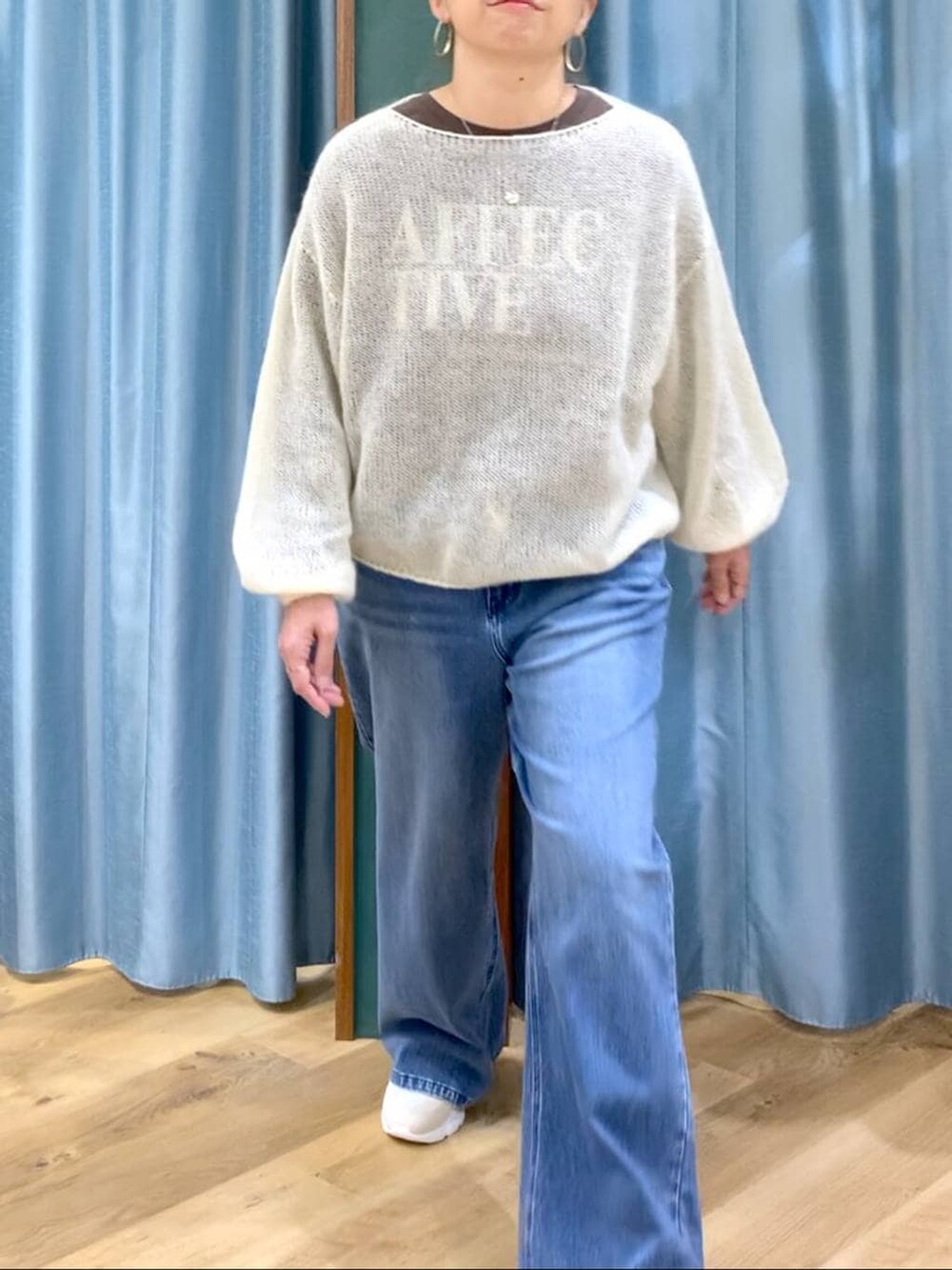 ブルー系のデニムパンツ、ホワイト系のニット/セーター、ホワイト系のスニーカーを着用したレディースの冬コーディネートの4枚目の写真