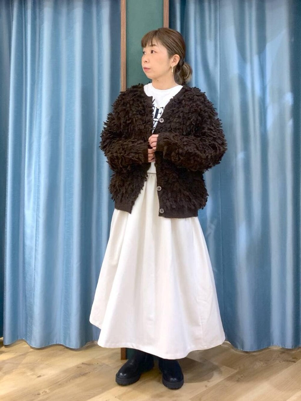 ブラック系のブーツ、ホワイト系のスカート、ブラウン系のカーディガン/ボレロを着用したレディースの冬コーディネートの2枚目の写真