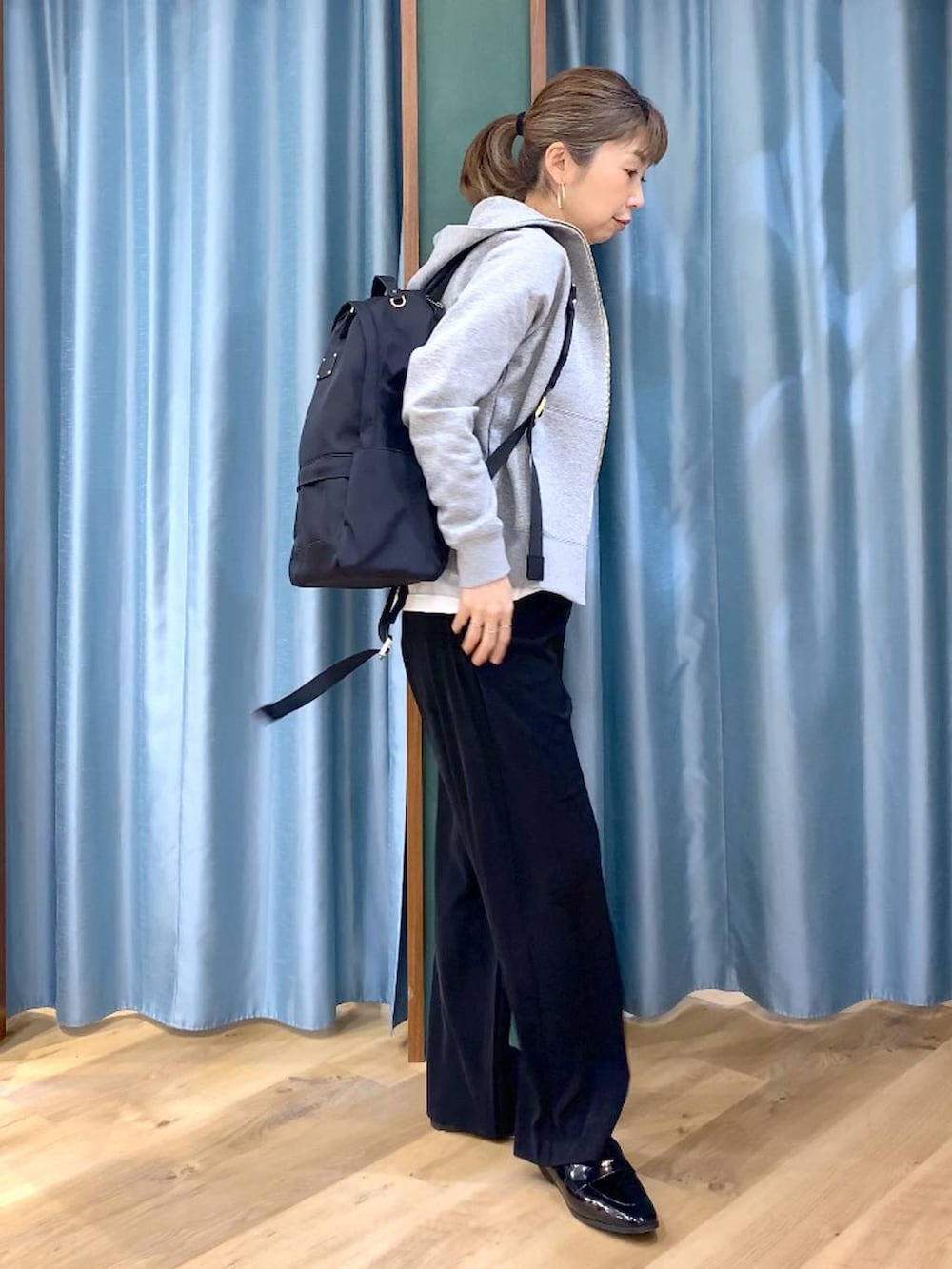 ブラック系のバックパック/リュック、ブラック系のスラックス、グレー系のパーカーを着用したレディースの春コーディネートの4枚目の写真