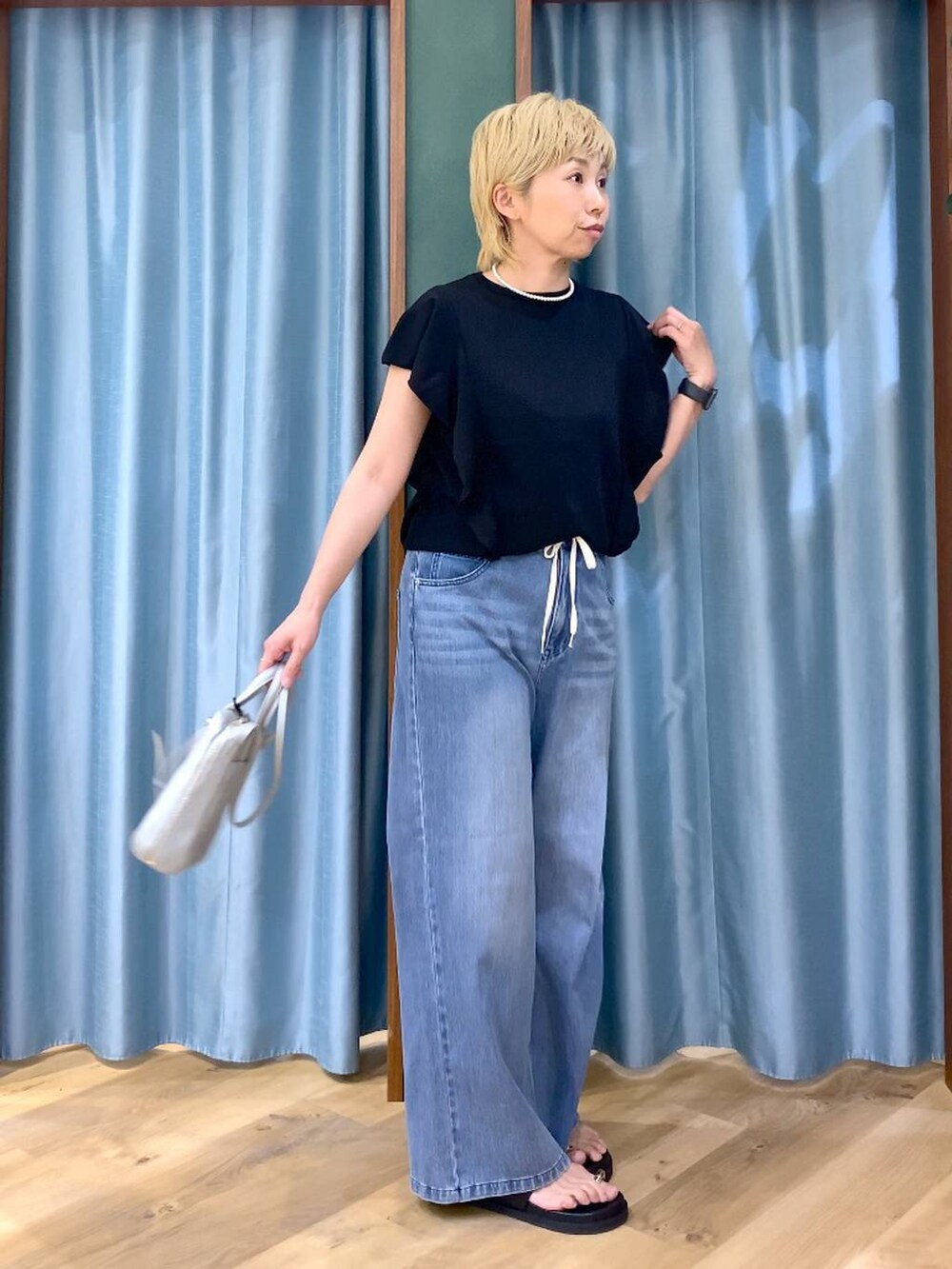 ブルー系のデニムパンツ、シルバー系のショルダーバッグ、ブラック系のニット/セーターを着用したレディースの夏コーディネートの6枚目の写真