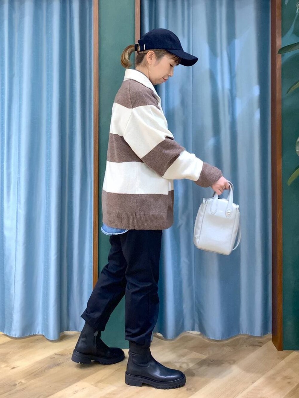 ブラック系のブーツ、ホワイト系のニット/セーター、ブルー系のシャツ/ブラウスを着用したレディースの冬コーディネートの3枚目の写真