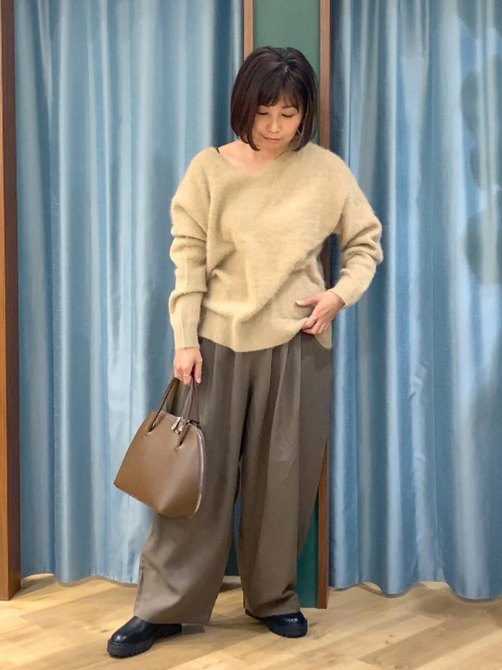 ブラック系のブーツ、ベージュ系のピーコート、ブラウン系のトートバッグを着用したレディースの秋コーディネートの7枚目の写真