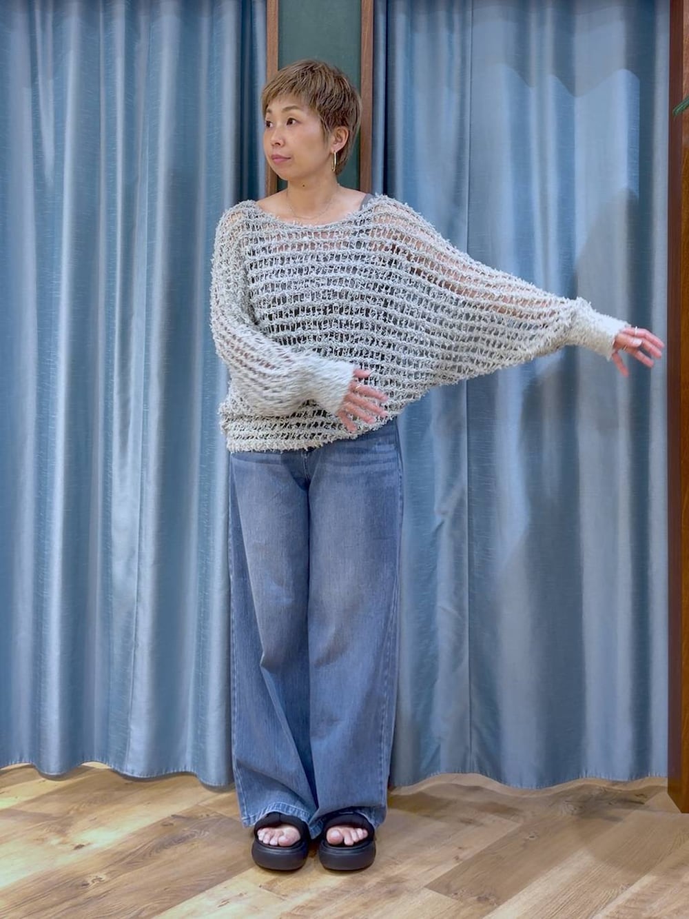 グレー系のタンクトップ、ブルー系のデニムパンツ、ブラック系のサンダルを着用したレディースの夏コーディネートの5枚目の写真