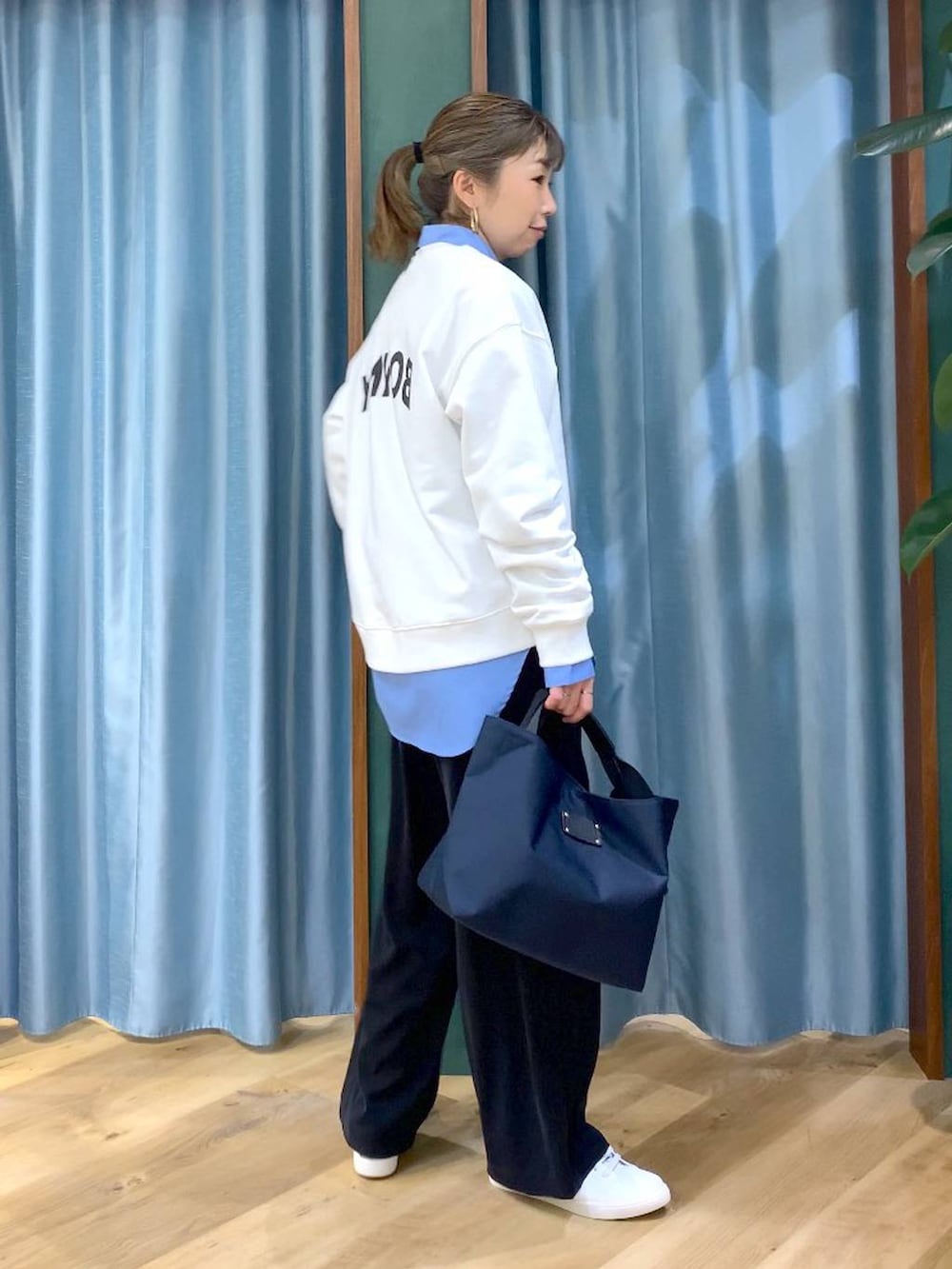 ブラック系のスラックス、ブルー系のトートバッグ、ブルー系のシャツ/ブラウスを着用したレディースの冬コーディネートの2枚目の写真