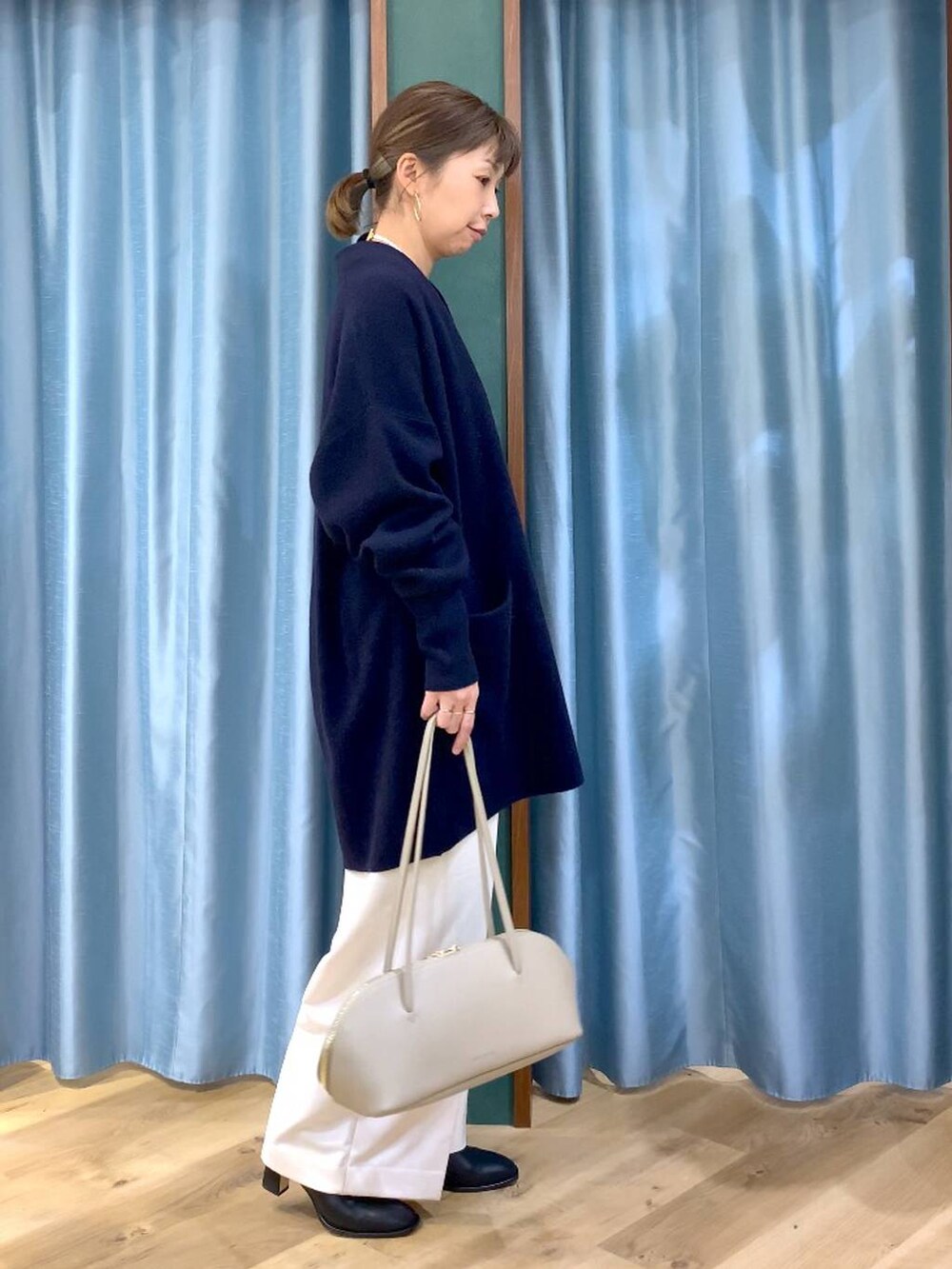 ベージュ系のトートバッグ、ブラック系のブーツ、ブルー系のニット/セーターを着用したレディースの冬コーディネートの2枚目の写真