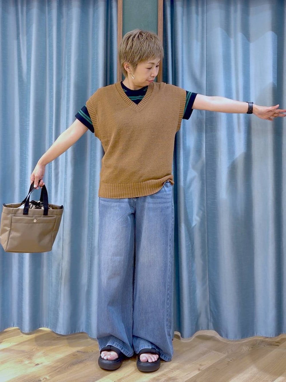 ブルー系のデニムパンツ、ベージュ系のショルダーバッグ、ブラック系のサンダルを着用したレディースの夏コーディネートの5枚目の写真
