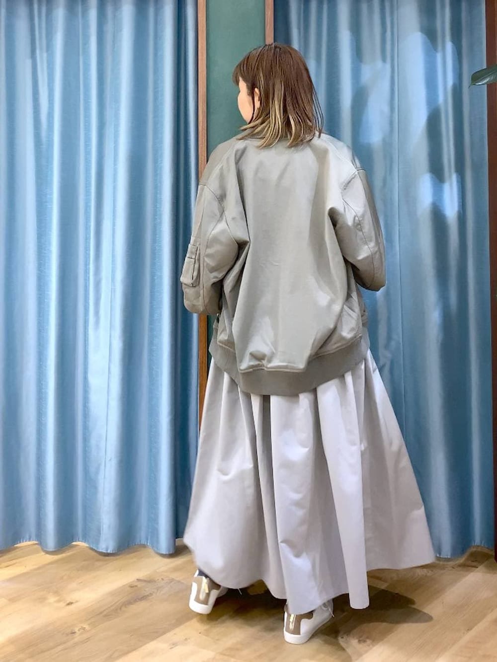 グレー系のスカート、グリーン系のMA-1、ホワイト系のTシャツ/カットソーを着用したレディースの冬コーディネートの5枚目の写真