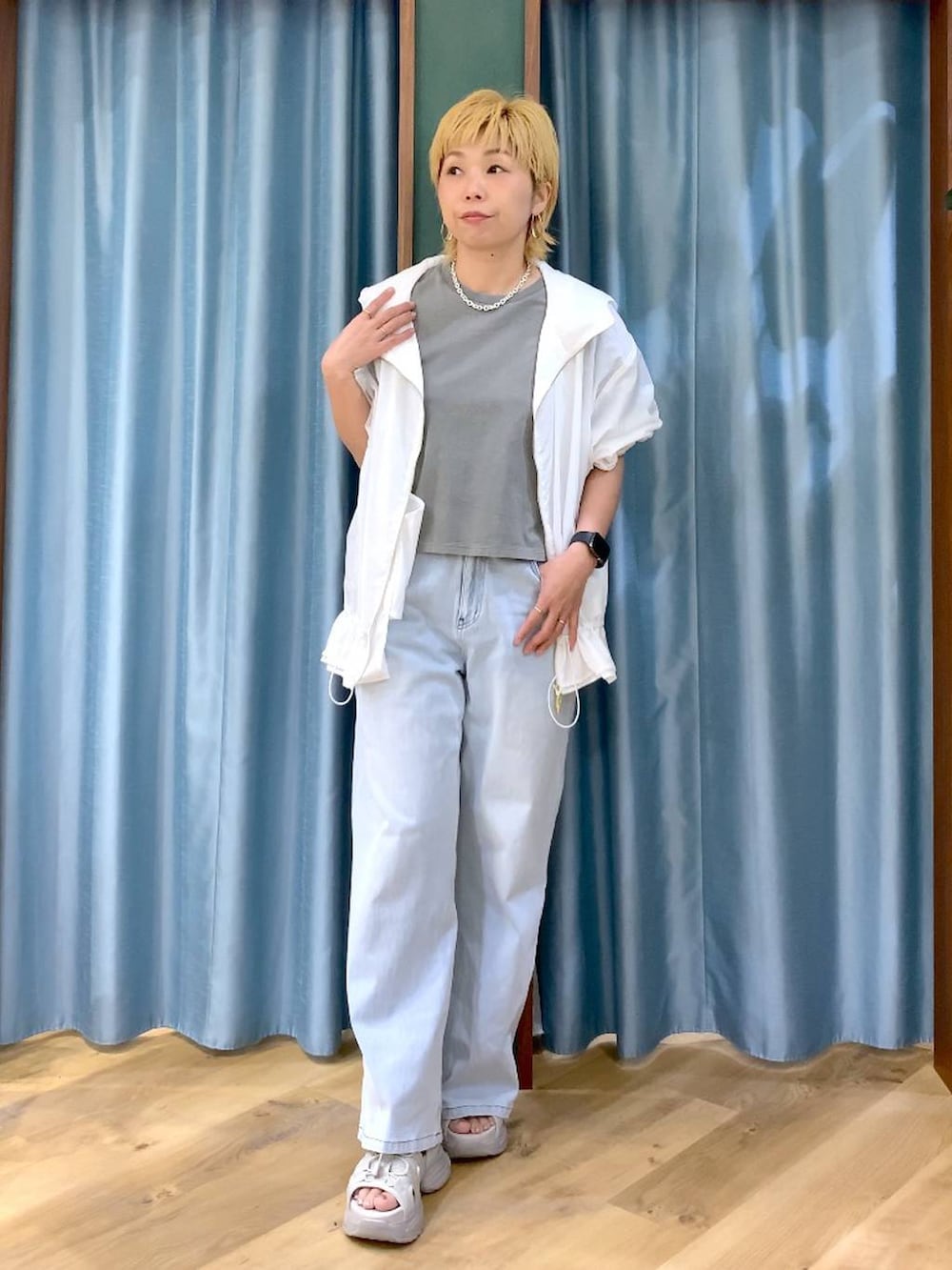 ブルー系のデニムパンツ、グレー系のサンダル、ホワイト系のブルゾンを着用したレディースの春コーディネートの2枚目の写真