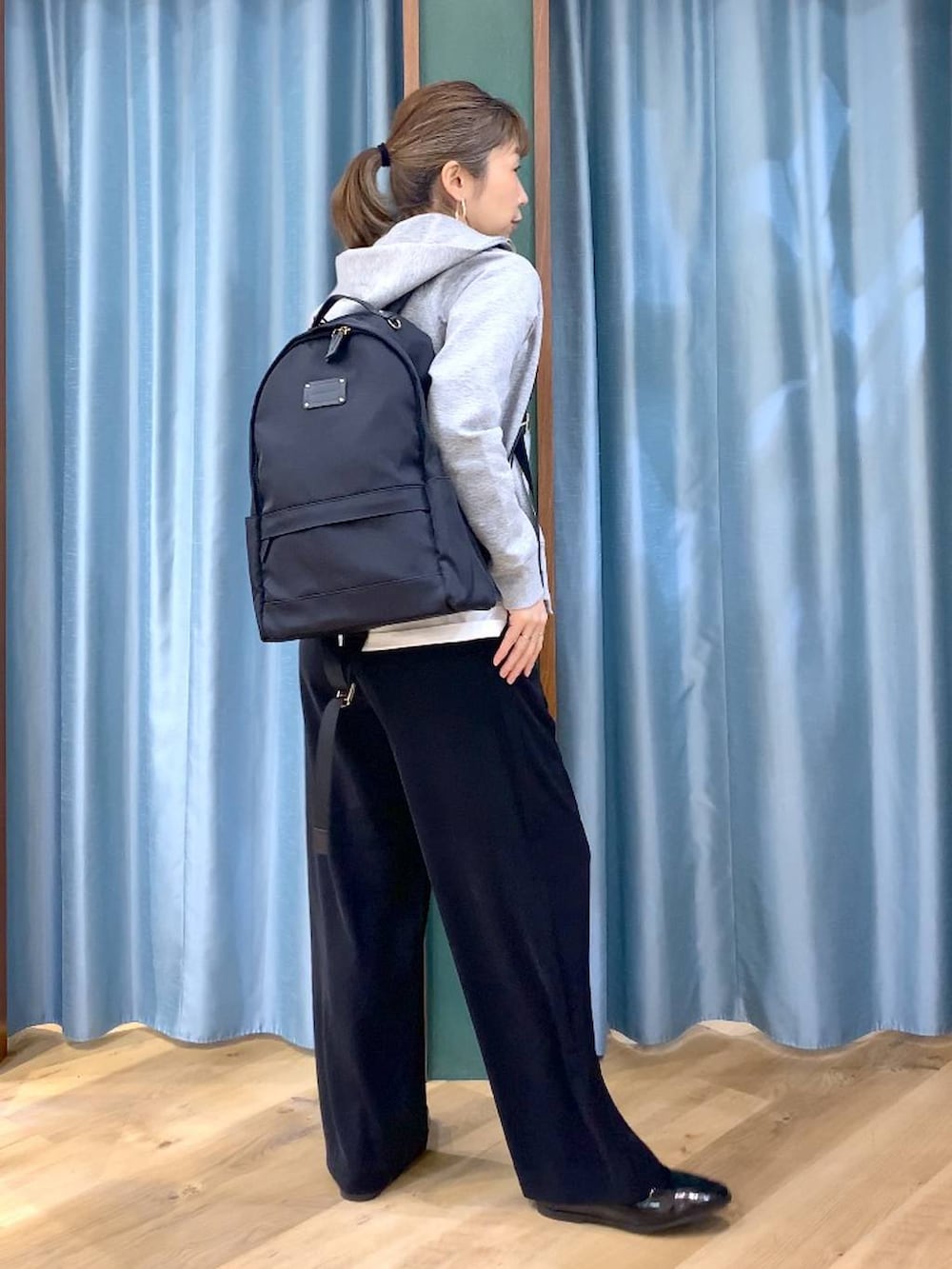 ブラック系のバックパック/リュック、ブラック系のスラックス、グレー系のパーカーを着用したレディースの春コーディネートの5枚目の写真