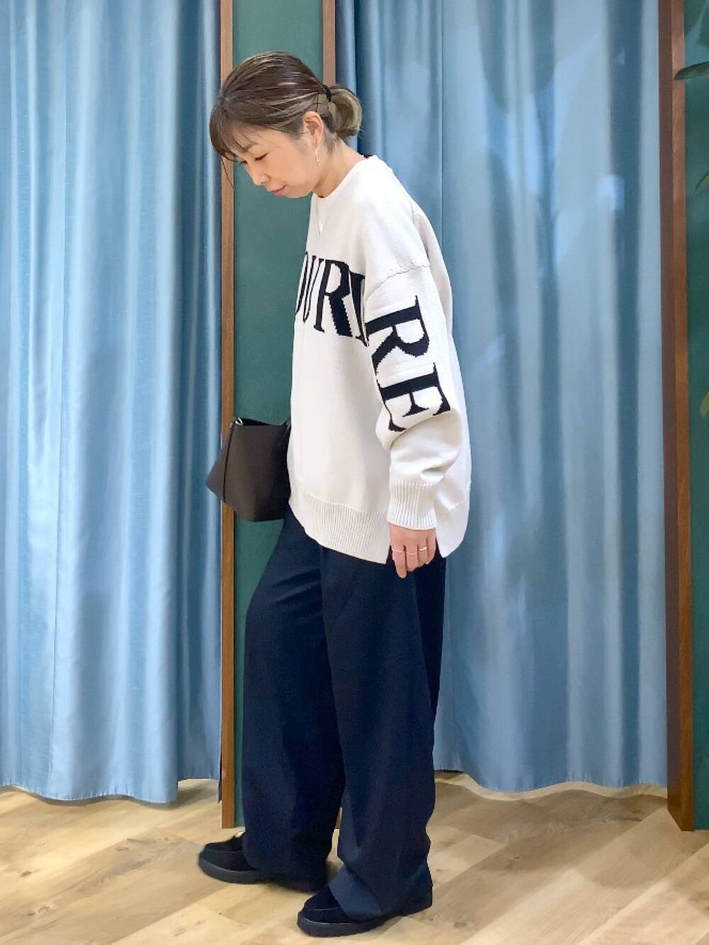 ベージュ系のニット/セーター、ブラック系のローファー、ホワイト系のTシャツ/カットソーを着用したレディースの秋コーディネートの2枚目の写真