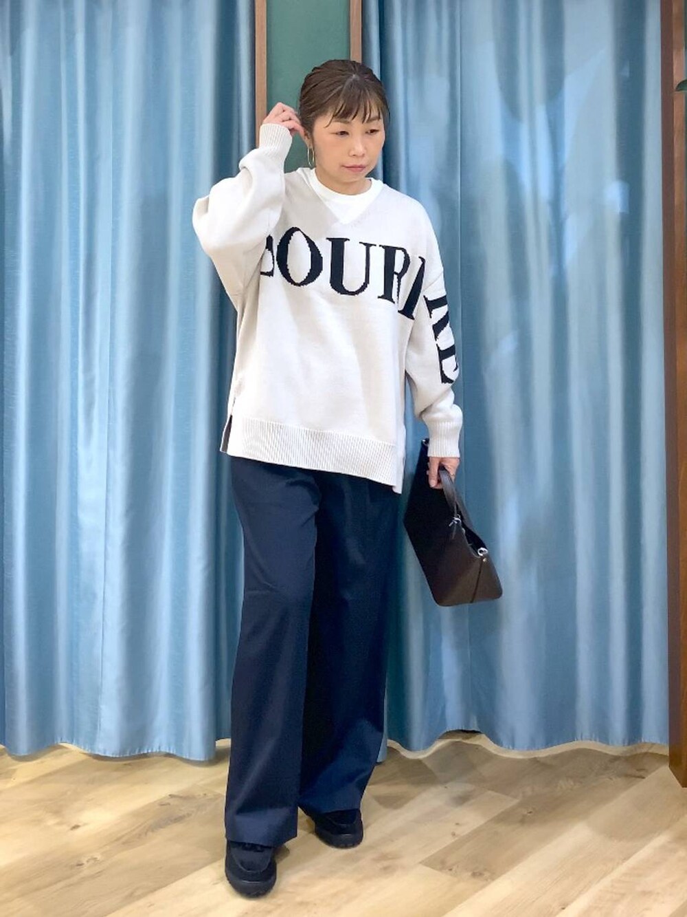 ベージュ系のニット/セーター、ブラック系のローファー、ホワイト系のTシャツ/カットソーを着用したレディースの秋コーディネートの4枚目の写真