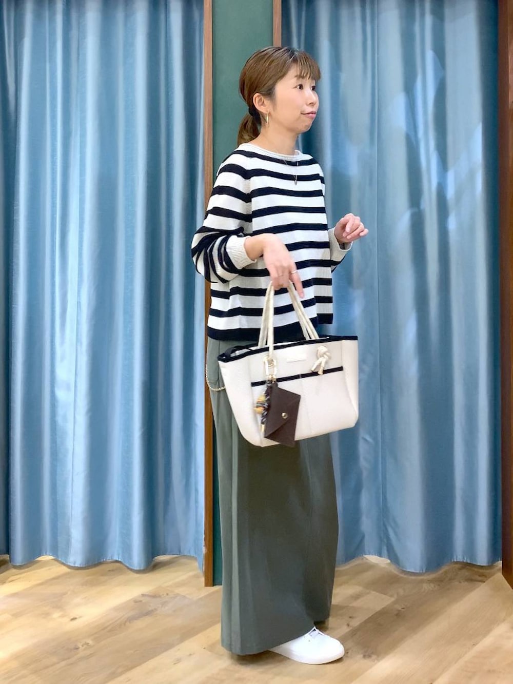 ベージュ系のニット/セーター、グリーン系のスカート、ホワイト系のトートバッグを着用したレディースの春コーディネートの6枚目の写真