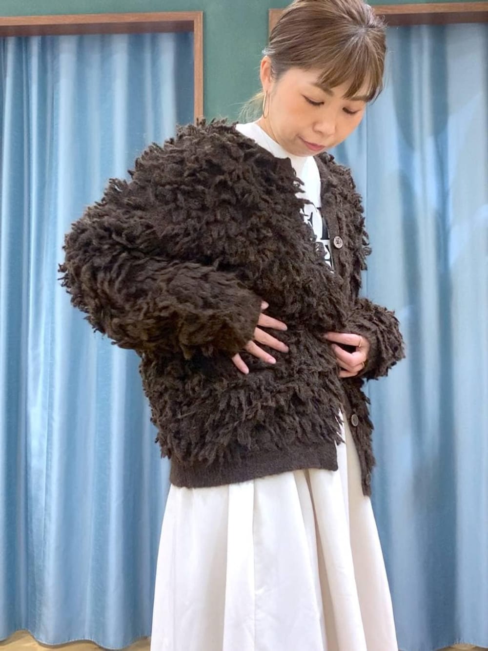 ブラック系のブーツ、ホワイト系のスカート、ブラウン系のカーディガン/ボレロを着用したレディースの冬コーディネートの6枚目の写真