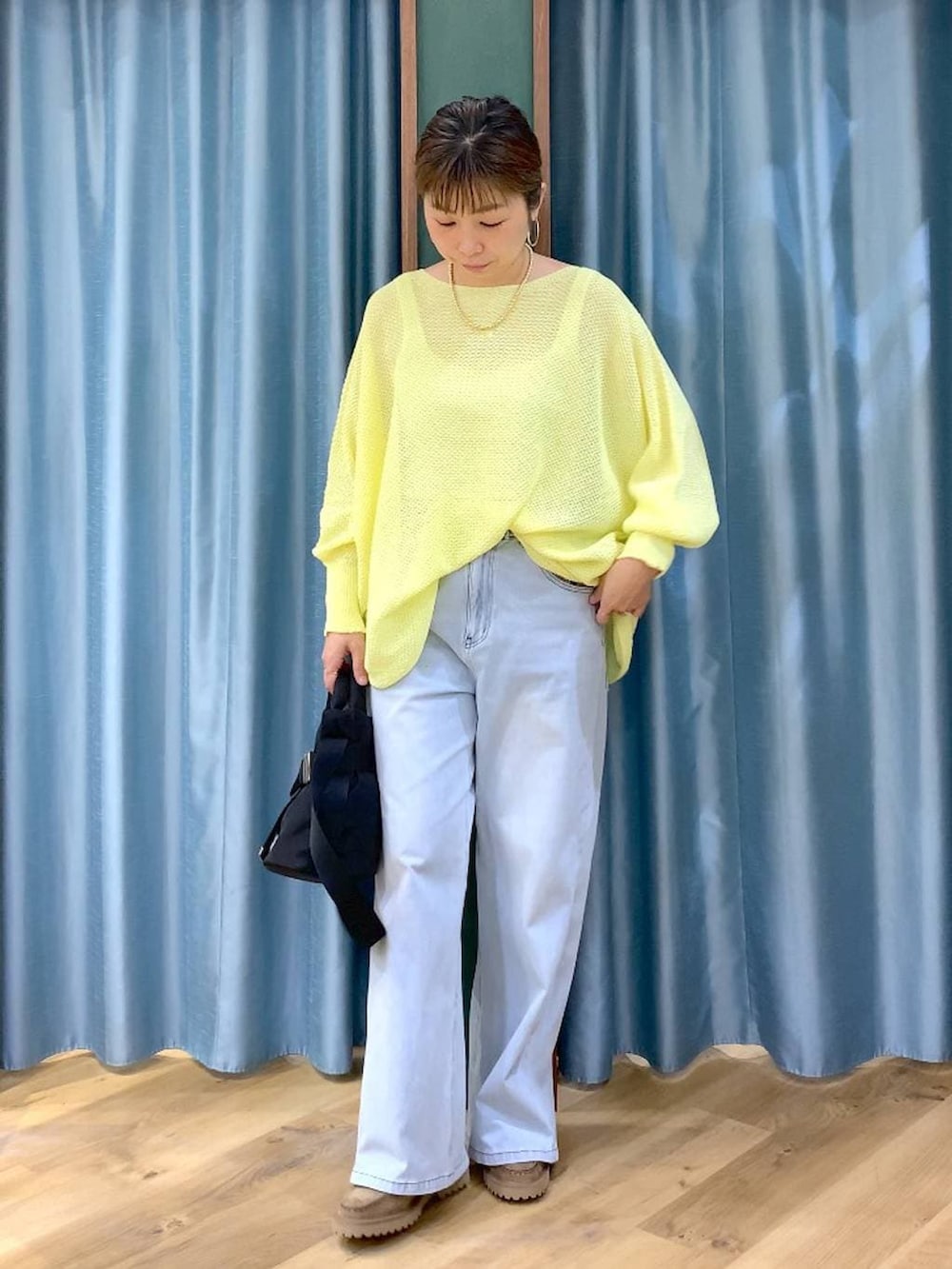 ブラック系のショルダーバッグ、ベージュ系のローファー、ブルー系のデニムパンツを着用したレディースの春コーディネートの2枚目の写真