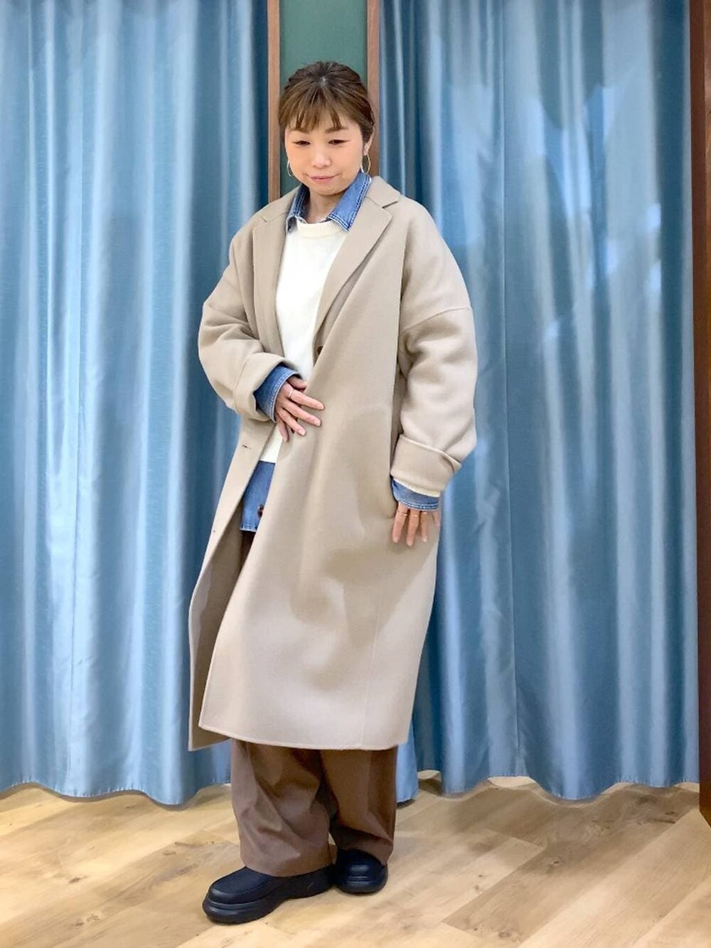 ブルー系のシャツ/ブラウス、ベージュ系のチェスターコート、ホワイト系のニット/セーターを着用したレディースの冬コーディネートの8枚目の写真