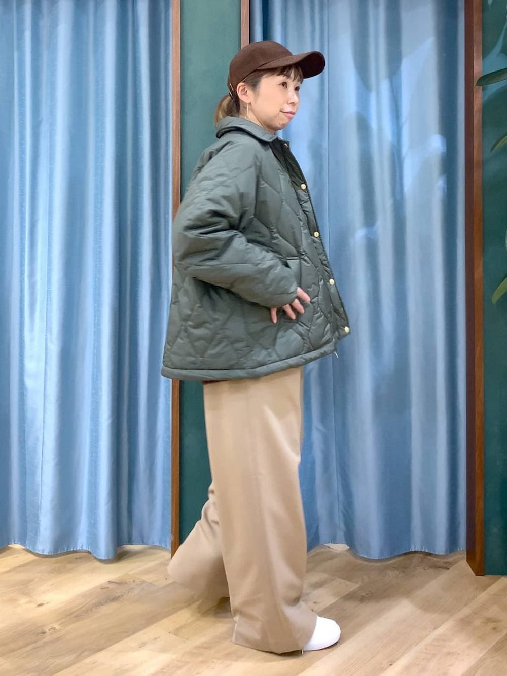 グリーン系のブルゾン、ブラウン系のニット/セーター、イエロー系のスラックスを着用したレディースの冬コーディネートの4枚目の写真