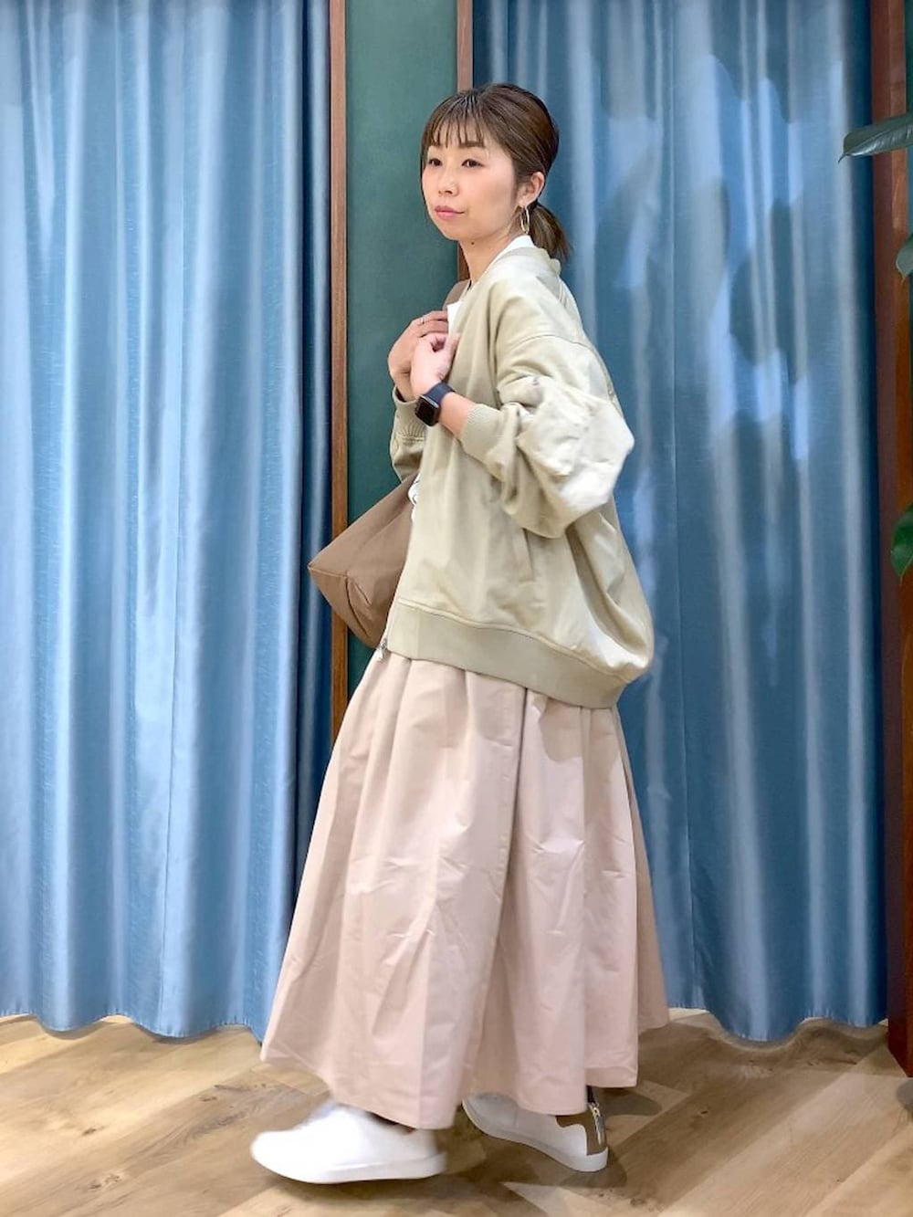 ブラウン系のショルダーバッグ、ベージュ系のスカート、ベージュ系のMA-1を着用したレディースの冬コーディネートの2枚目の写真