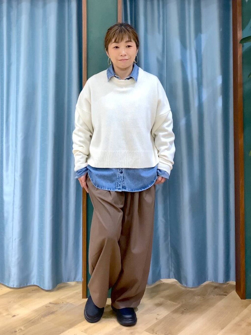 ブルー系のシャツ/ブラウス、ホワイト系のニット/セーター、ブラック系のブーツを着用したレディースの冬コーディネートの2枚目の写真