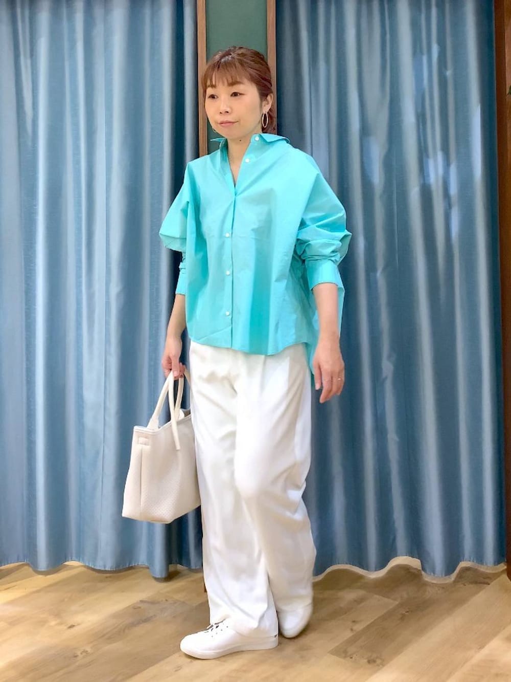 ホワイト系のスラックス、ブルー系のシャツ/ブラウス、ブラウン系のスニーカーを着用したレディースの春コーディネートの3枚目の写真