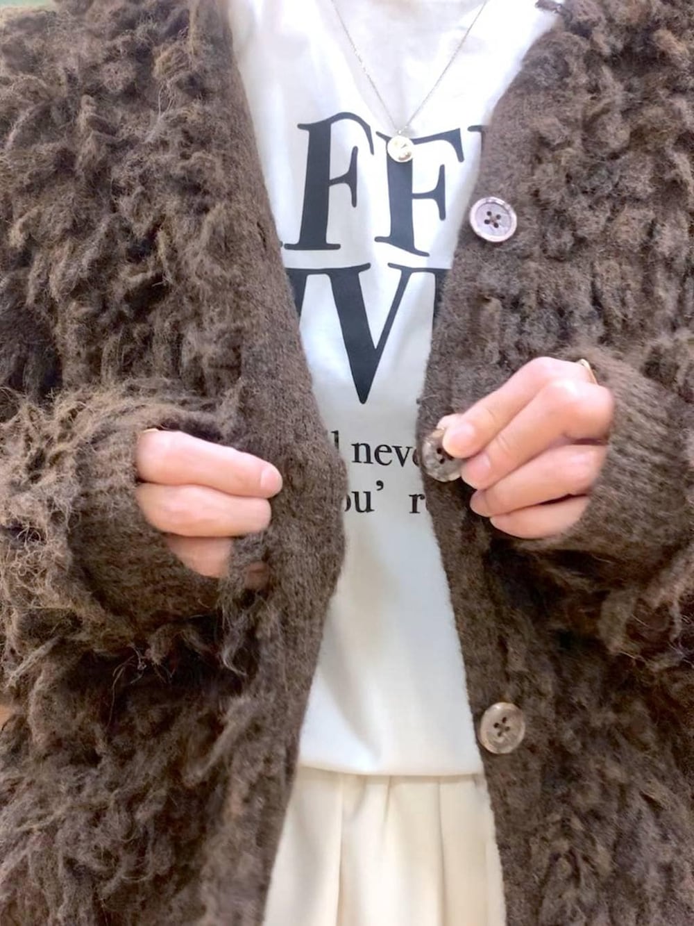 ブラック系のブーツ、ホワイト系のスカート、ブラウン系のカーディガン/ボレロを着用したレディースの冬コーディネートの7枚目の写真