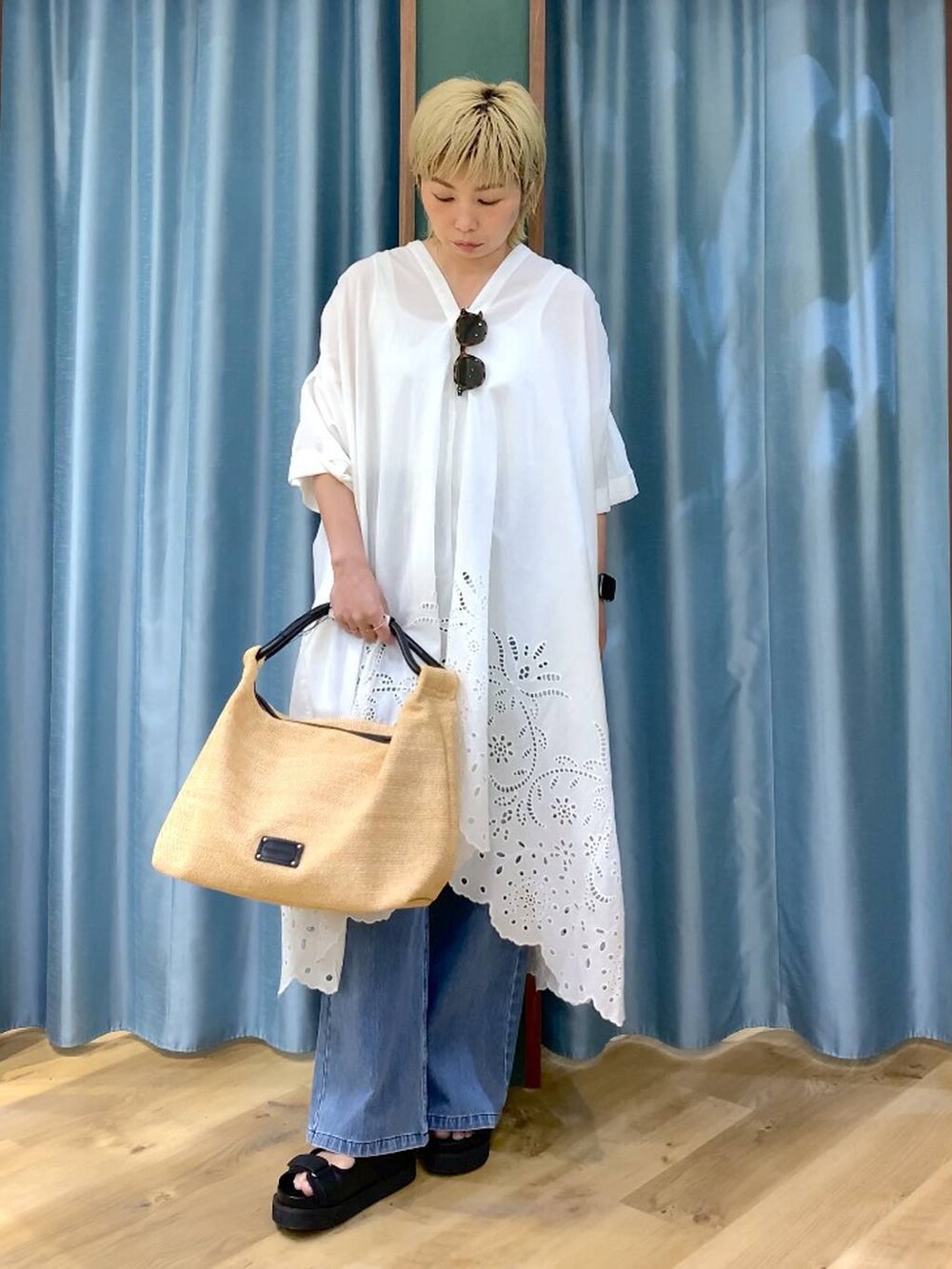 ブルー系のデニムパンツ、ブラック系のサンダル、ベージュ系のトートバッグを着用したレディースの夏コーディネートの2枚目の写真