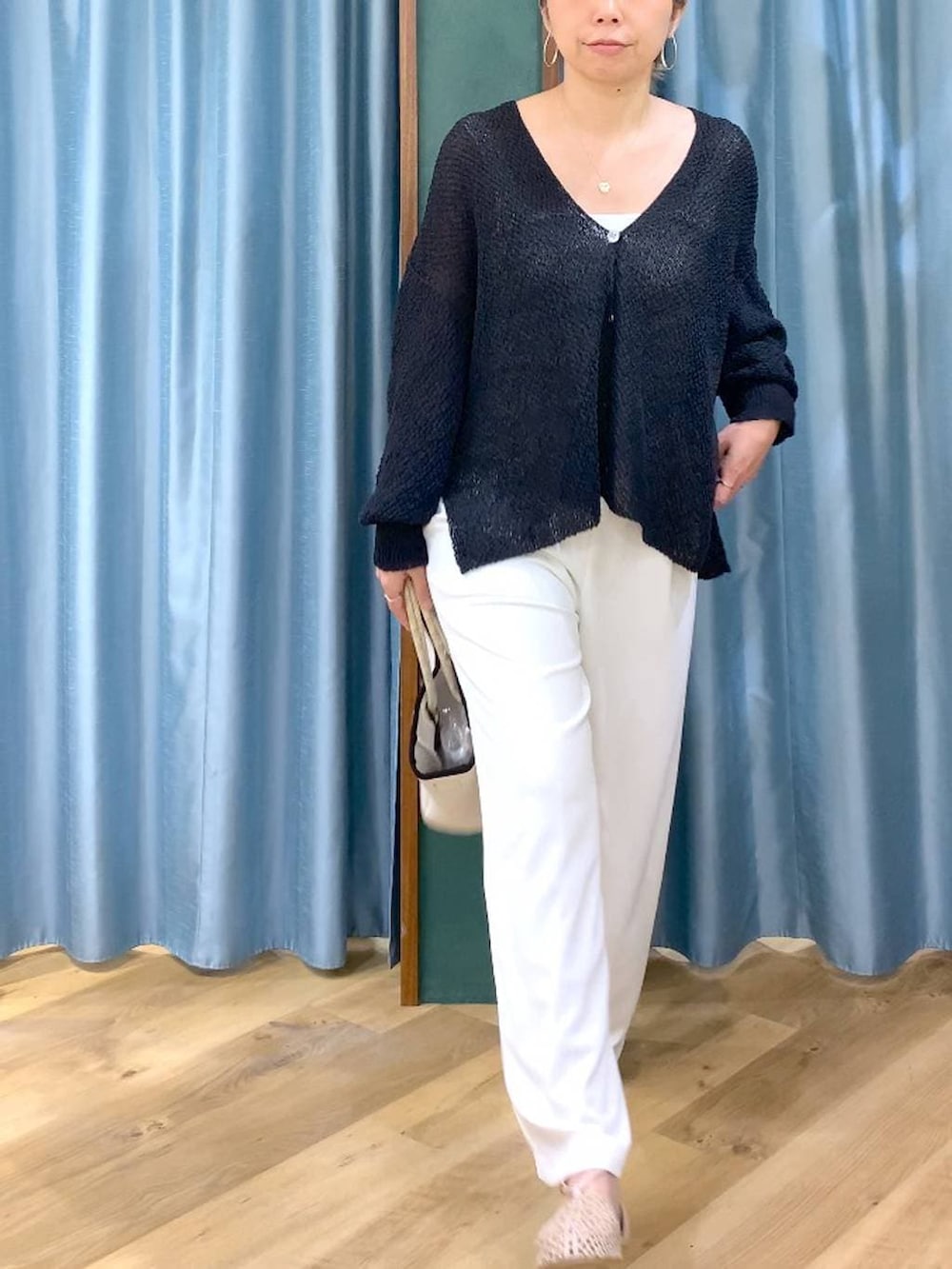 ホワイト系のスラックス、ブラック系のカーディガン/ボレロ、ホワイト系のトートバッグを着用したレディースの春コーディネートの7枚目の写真