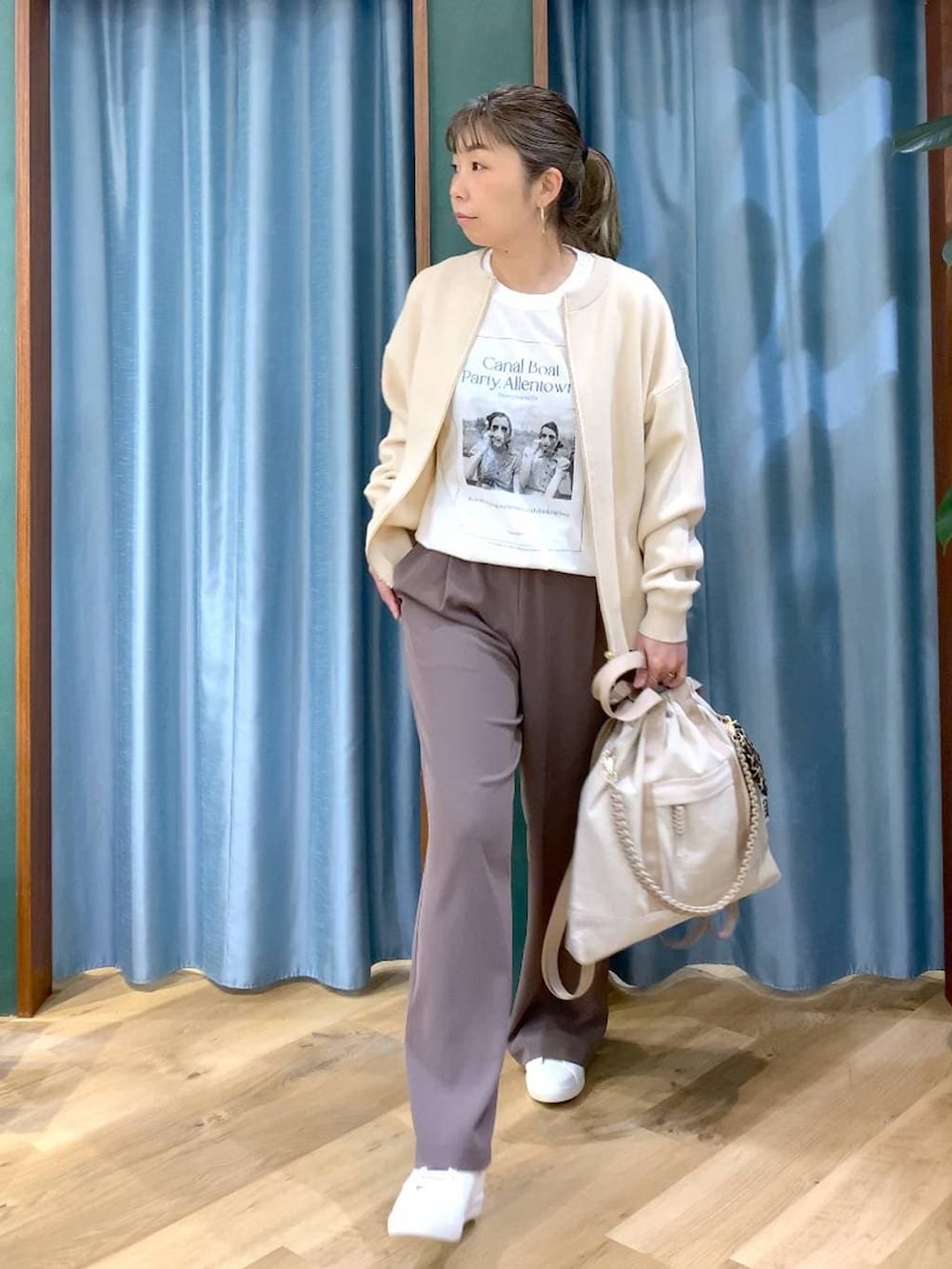 グリーン系のスラックス、ホワイト系のカーディガン/ボレロ、ベージュ系のバックパック/リュックを着用したレディースの冬コーディネートの5枚目の写真