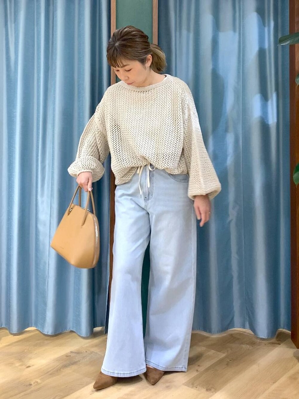 ベージュ系のニット/セーター、ブラウン系のトートバッグ、ホワイト系のTシャツ/カットソーを着用したレディースの冬コーディネートの4枚目の写真