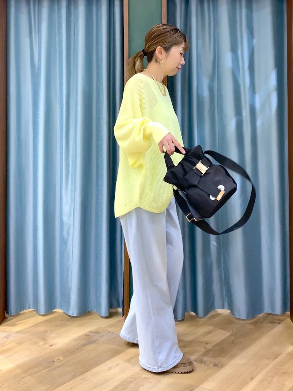 ブラック系のショルダーバッグ、ベージュ系のローファー、ブルー系のデニムパンツを着用したレディースの春コーディネートの3枚目の写真