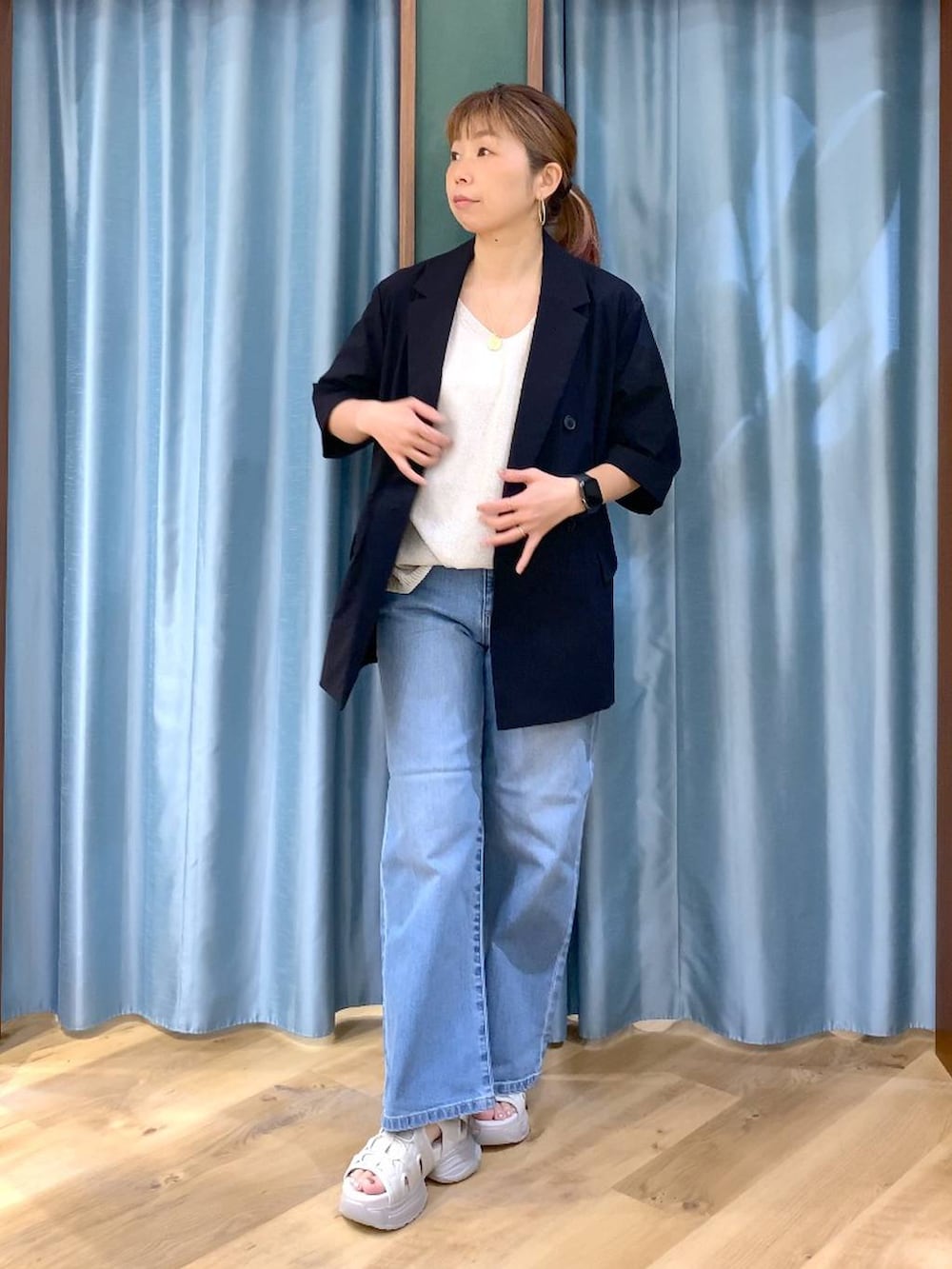 ブルー系のデニムパンツ、ホワイト系のタンクトップ、ブラック系のテーラードジャケットを着用したレディースの春コーディネートの3枚目の写真