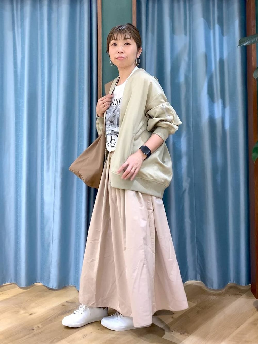 ブラウン系のショルダーバッグ、ベージュ系のスカート、ベージュ系のMA-1を着用したレディースの冬コーディネートの4枚目の写真