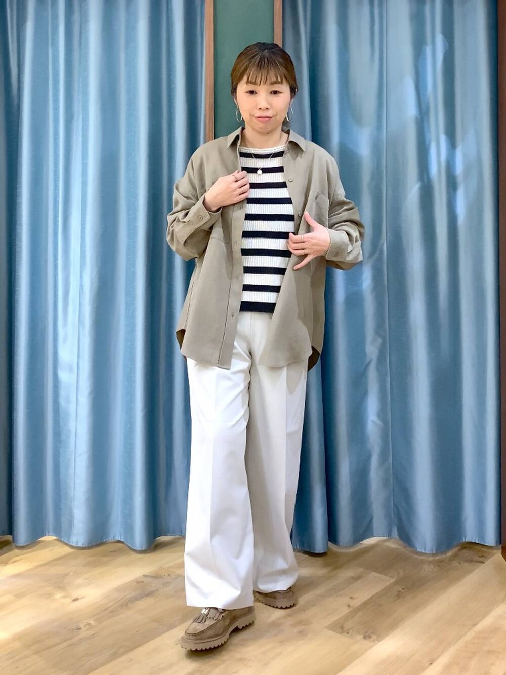 ベージュ系のローファー、グリーン系のシャツ/ブラウス、ベージュ系のニット/セーターを着用したレディースの春コーディネートの2枚目の写真